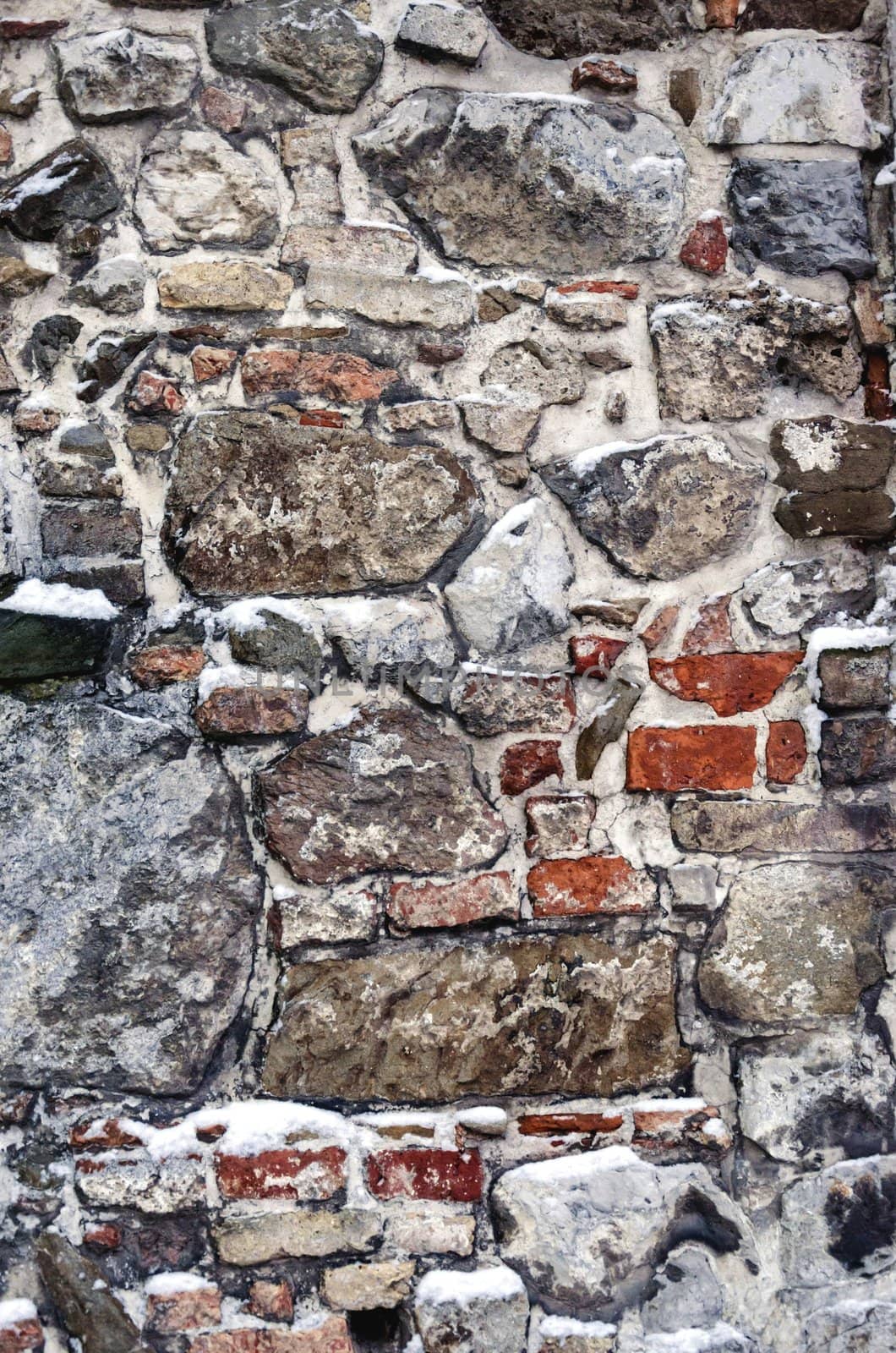 Old wall made from irregular pieces of different stones and bricks.