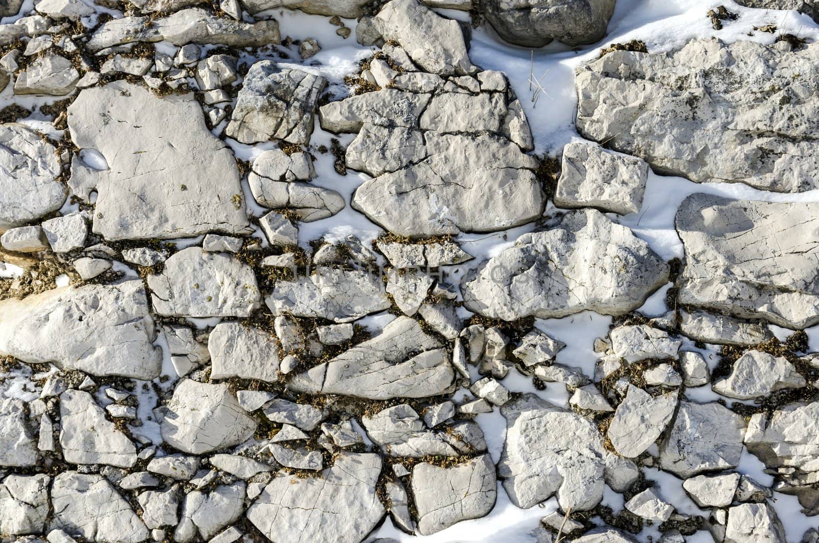 Old stone wall with moss and snow.