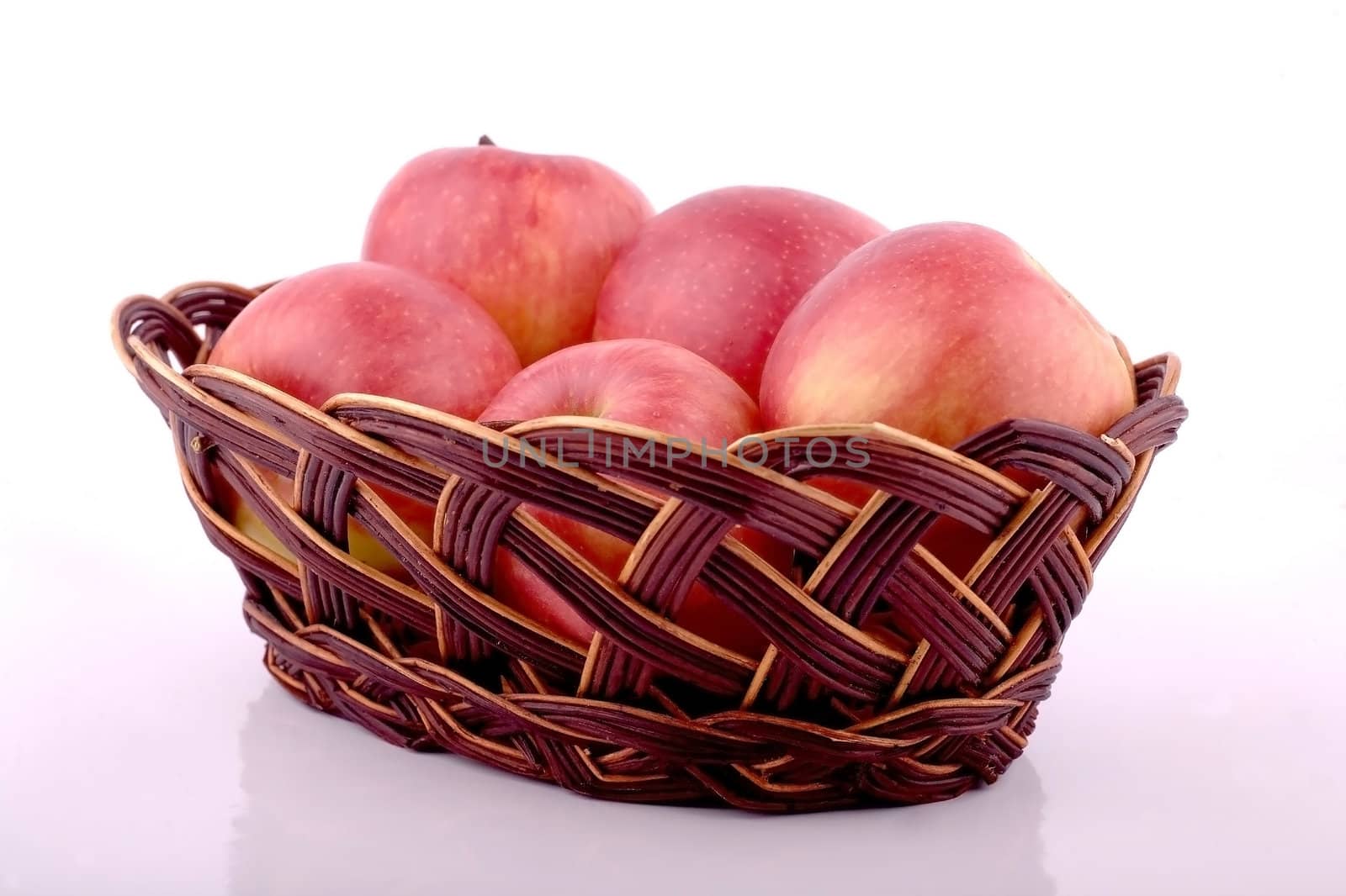 Red apples in a brown wicker basket on a white background