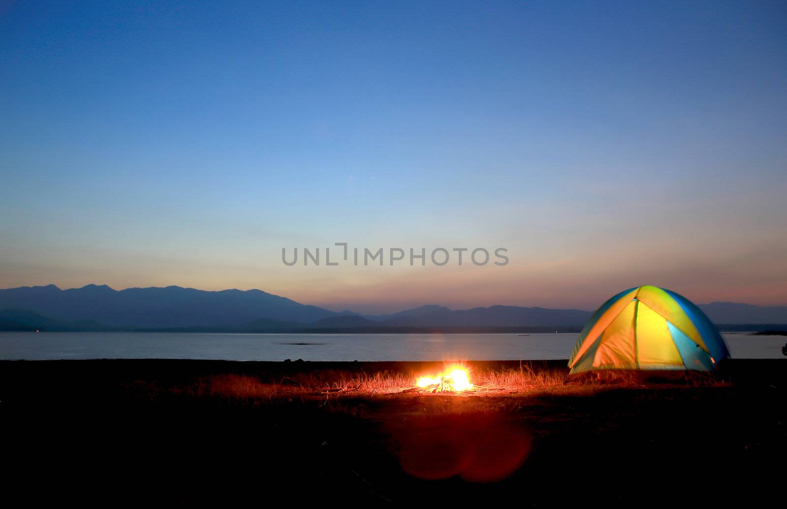 tent and campfire at sunset,beside the lake by rufous