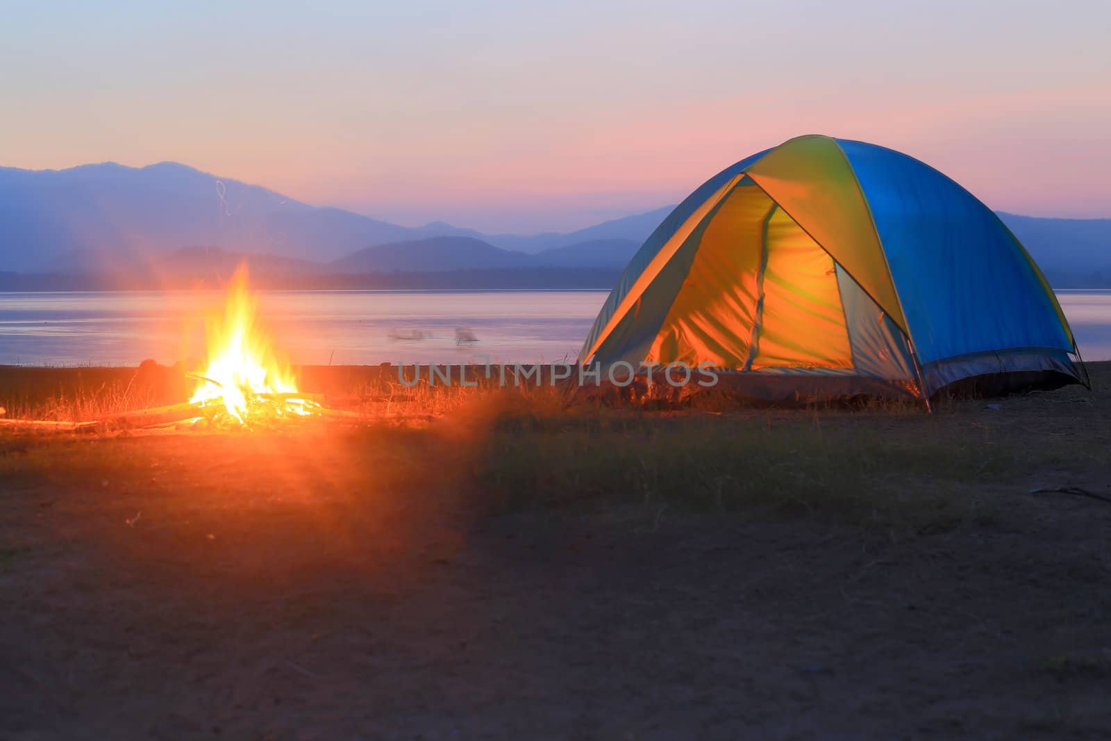 tent and campfire at sunset,beside the lake by rufous