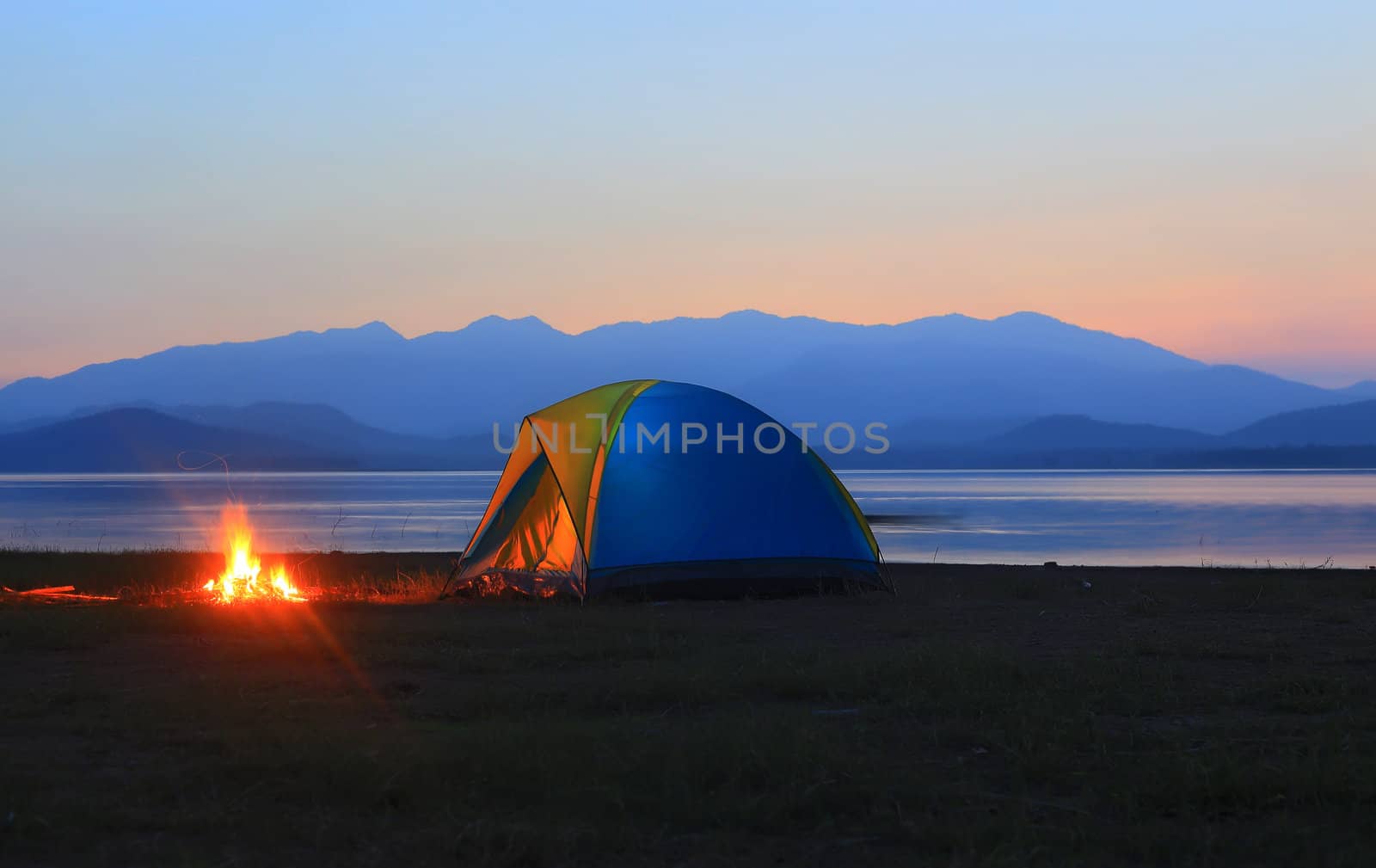 tent and campfire at sunset,beside the lake by rufous