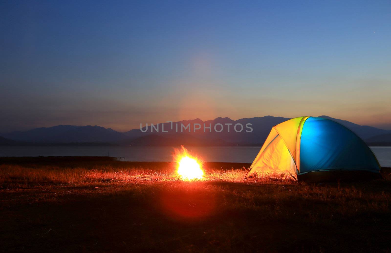 tent and campfire at sunset,beside the lake by rufous