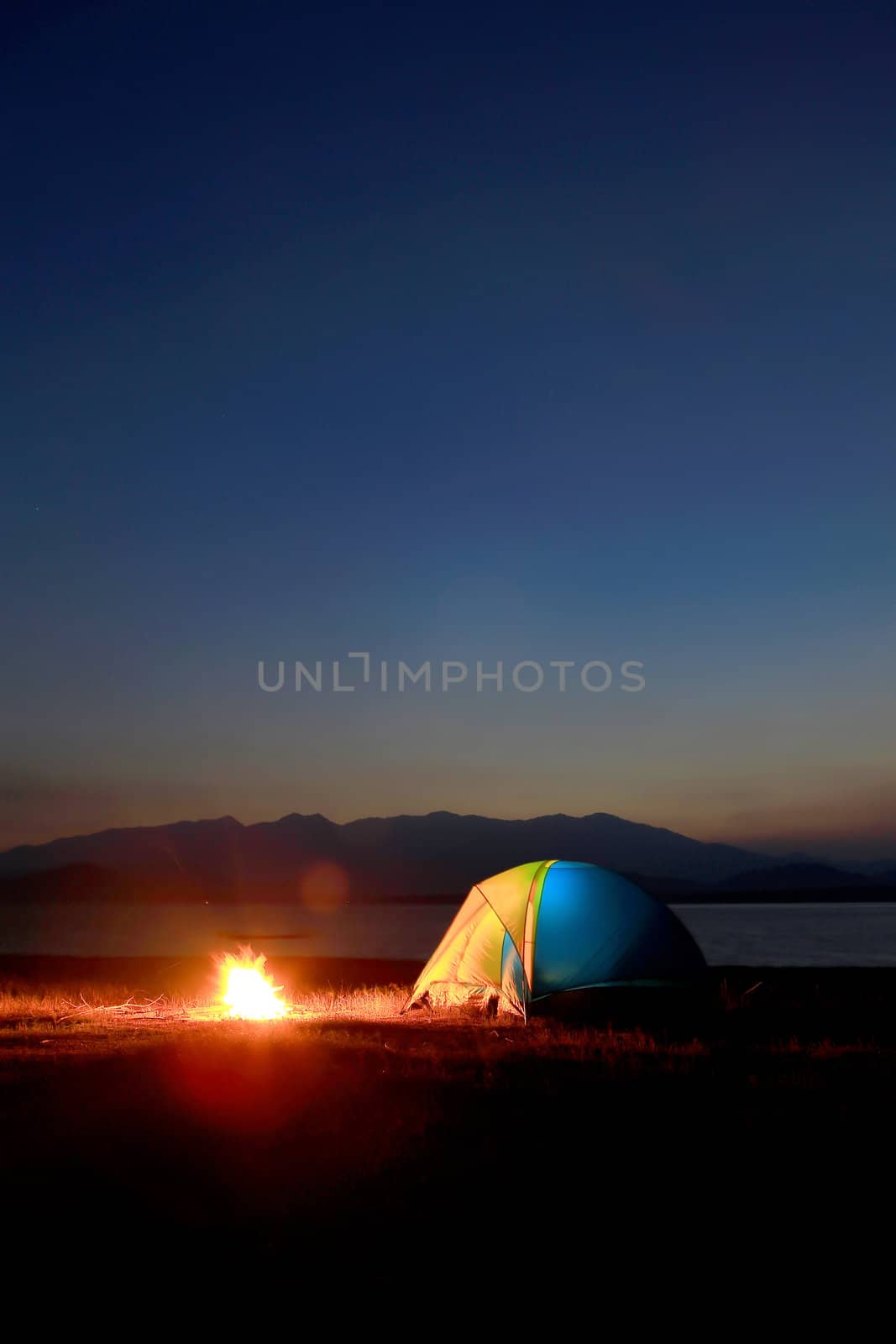 tent and campfire at sunset,beside the lake by rufous