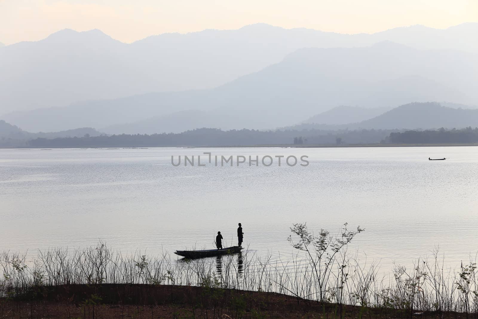 silhouette of fisherman on wood boat at lake.