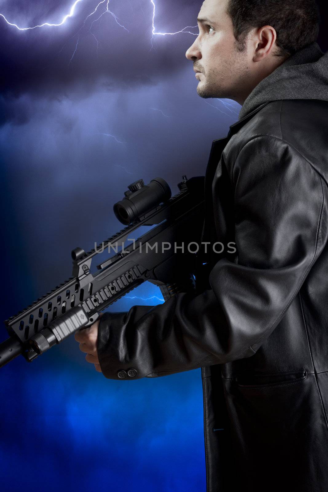 Man with long leather jacket and assault rifle over storm background