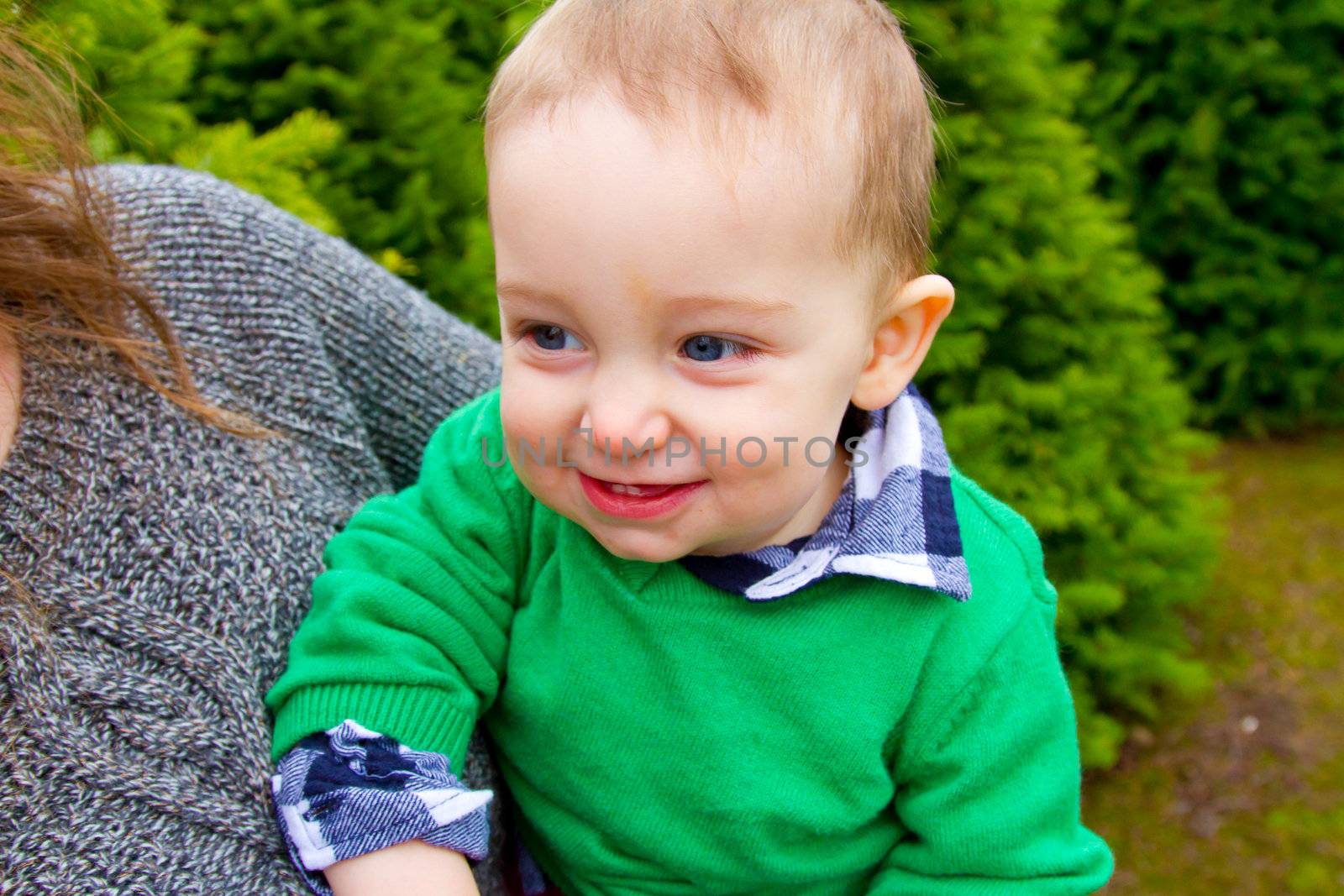 A cute young boy in a green shirt is having fun at a Christmas tree farm in Oregon.