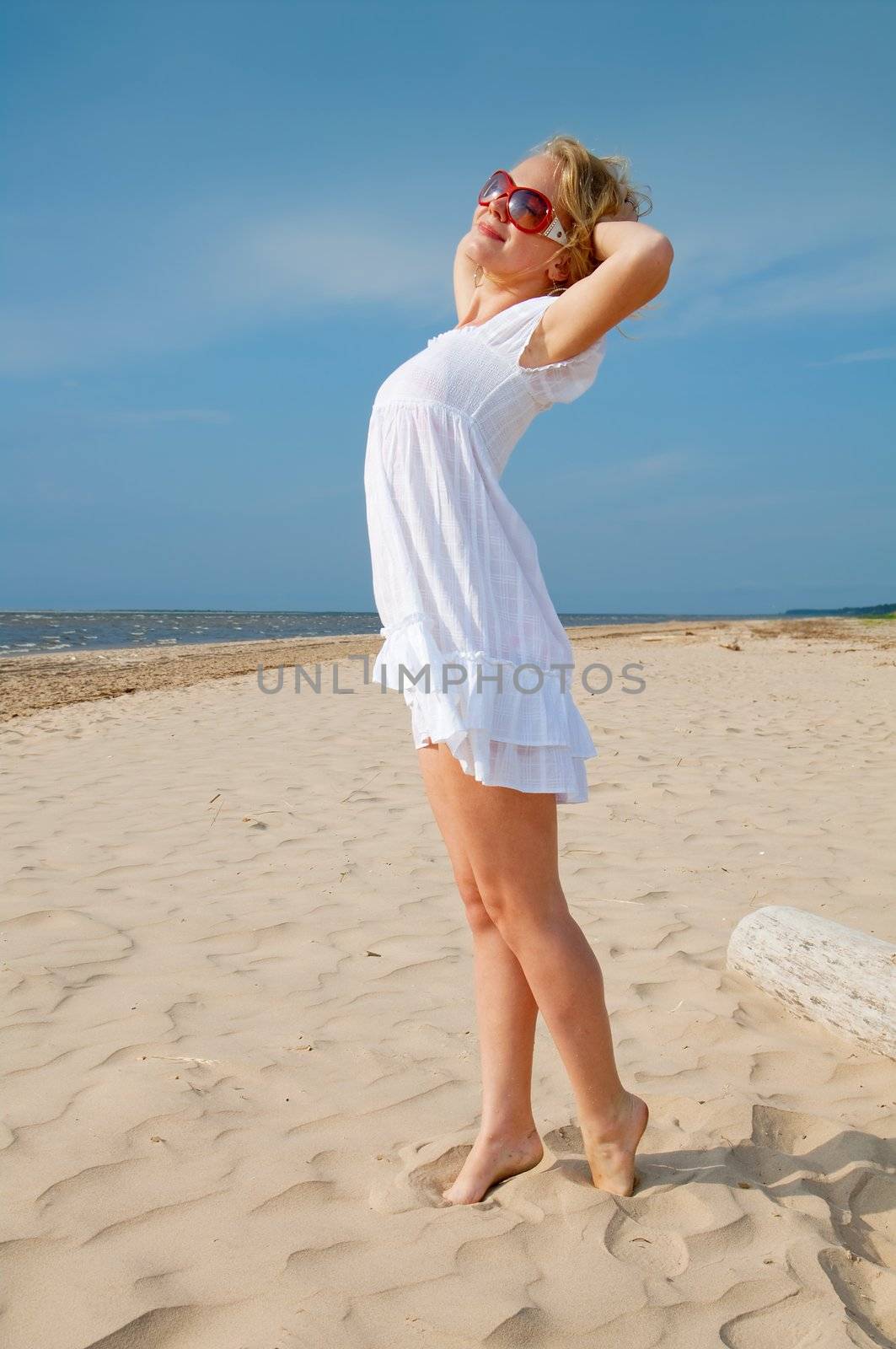 Young woman in summer dress standing on sand