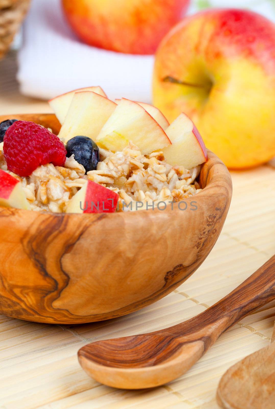 tasty oatmeal with raspberries and apple in the wooden bowl