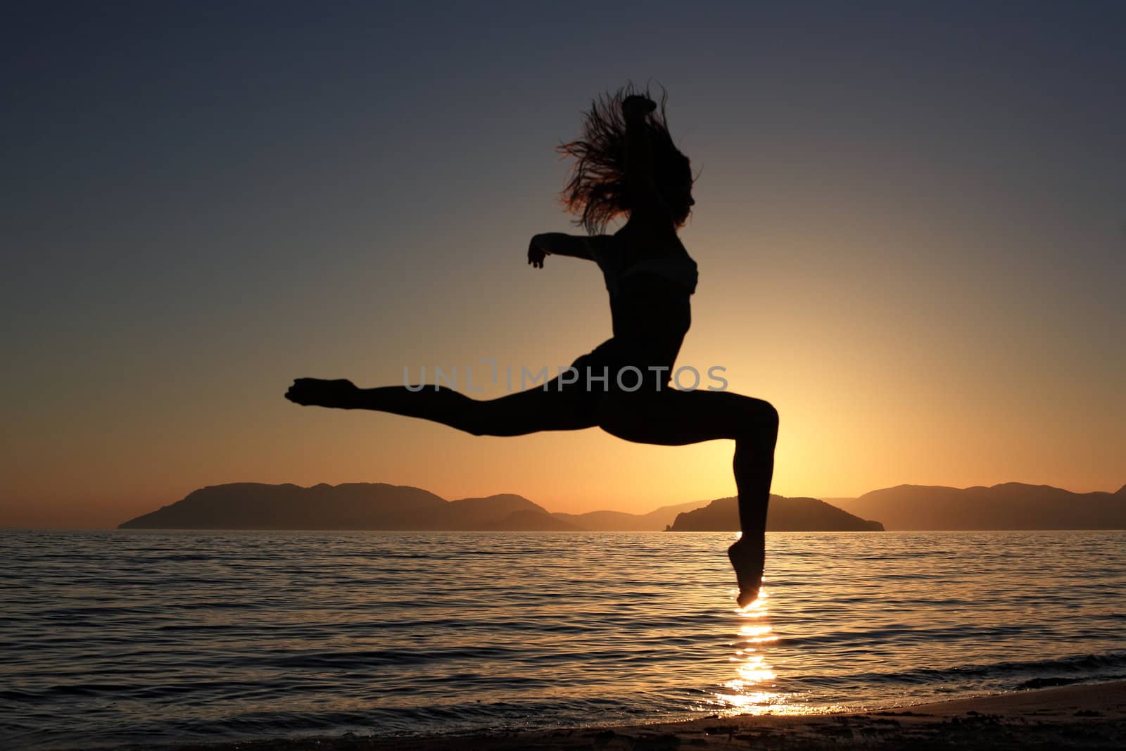 sunset and silhouette of a beautiful dancer in the beach