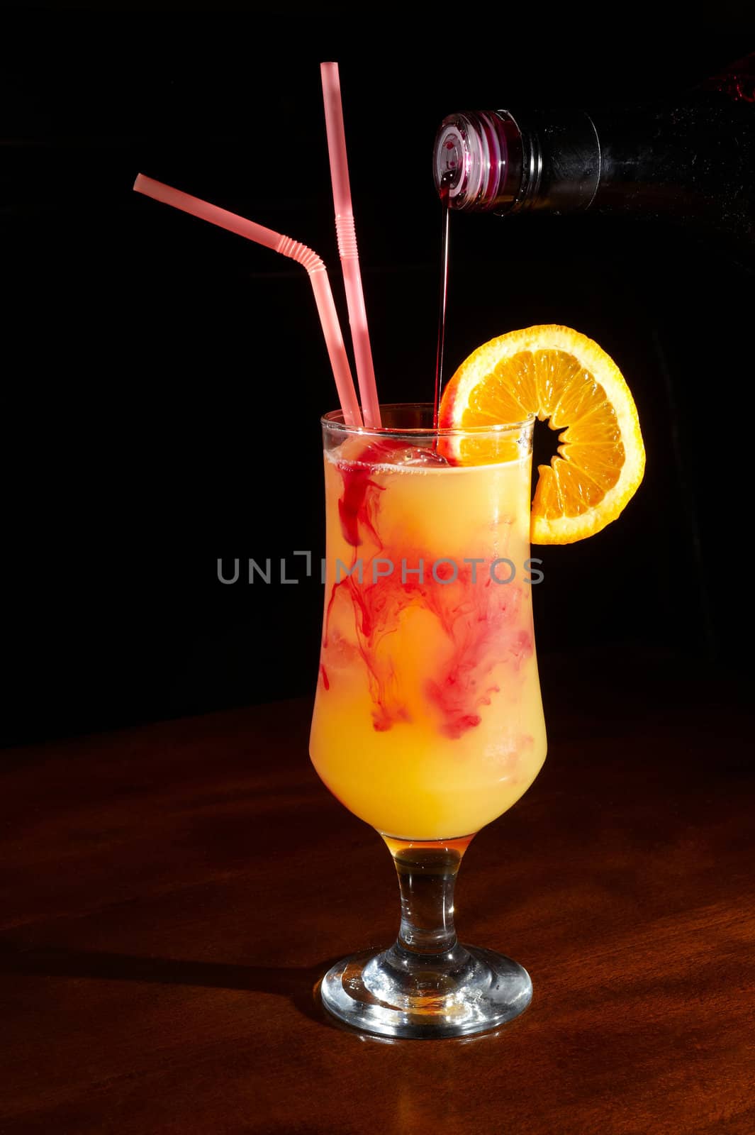 orange juice on a cocktail glass with a slice of orange and grenadine liquor droped in