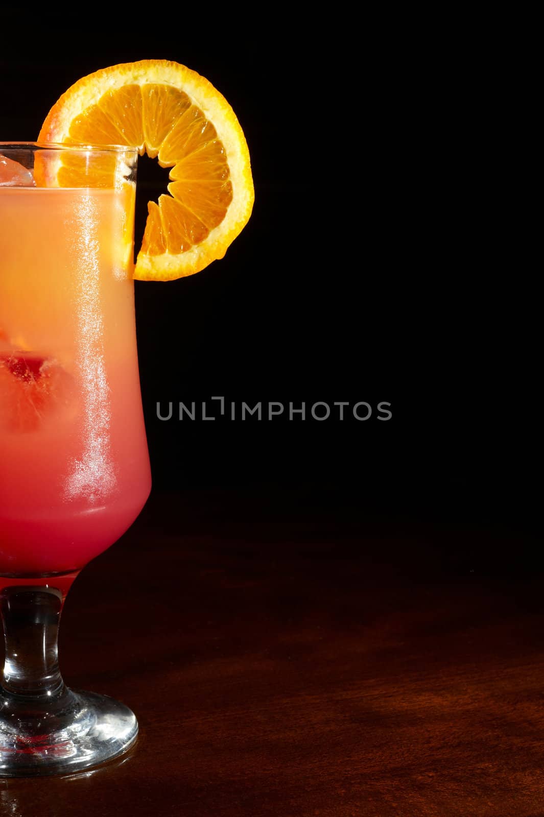 close up of orange juice on a cocktail glass with a slice of orange and grenadine liquor droped in