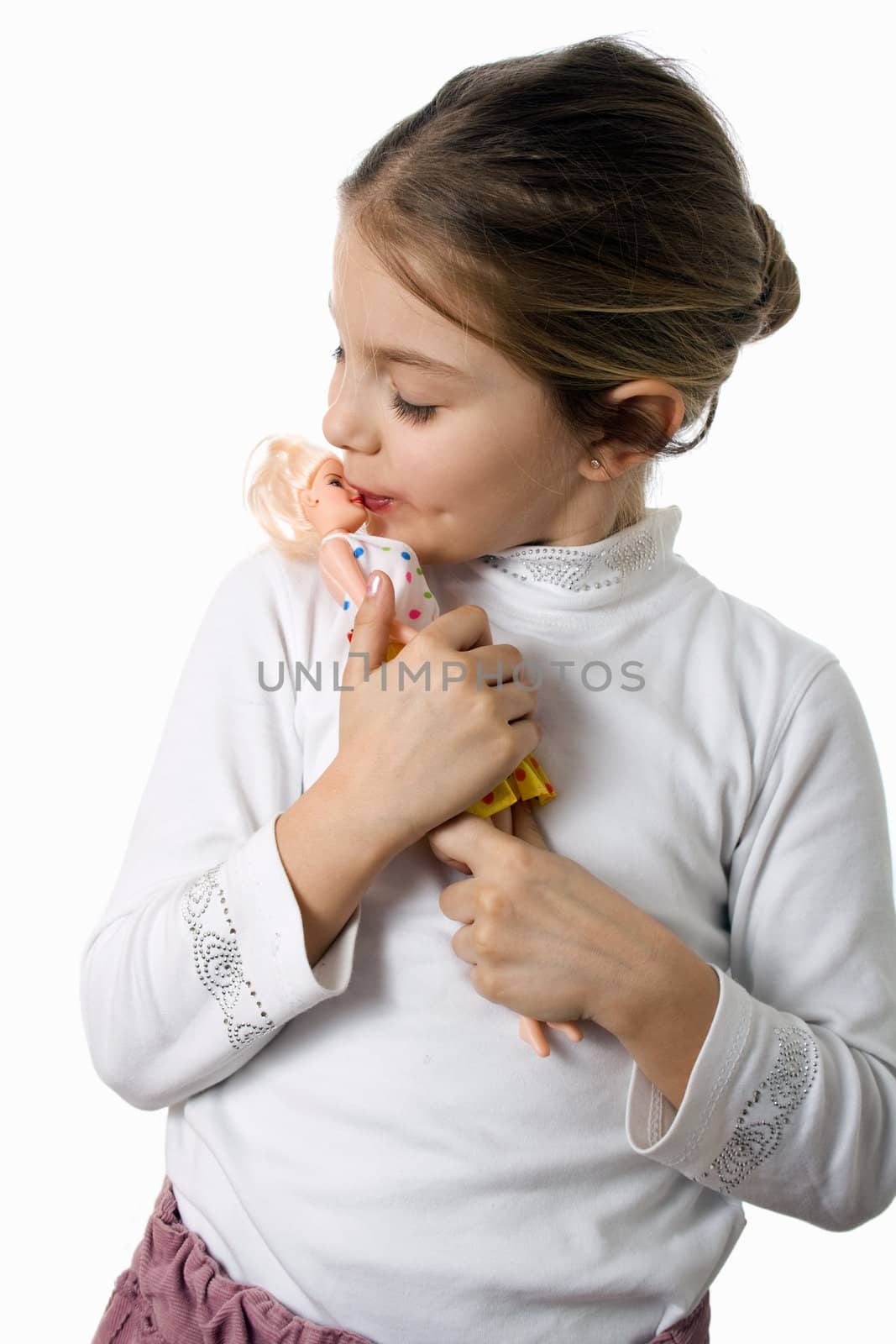 Little girl plays with a doll, kissing her