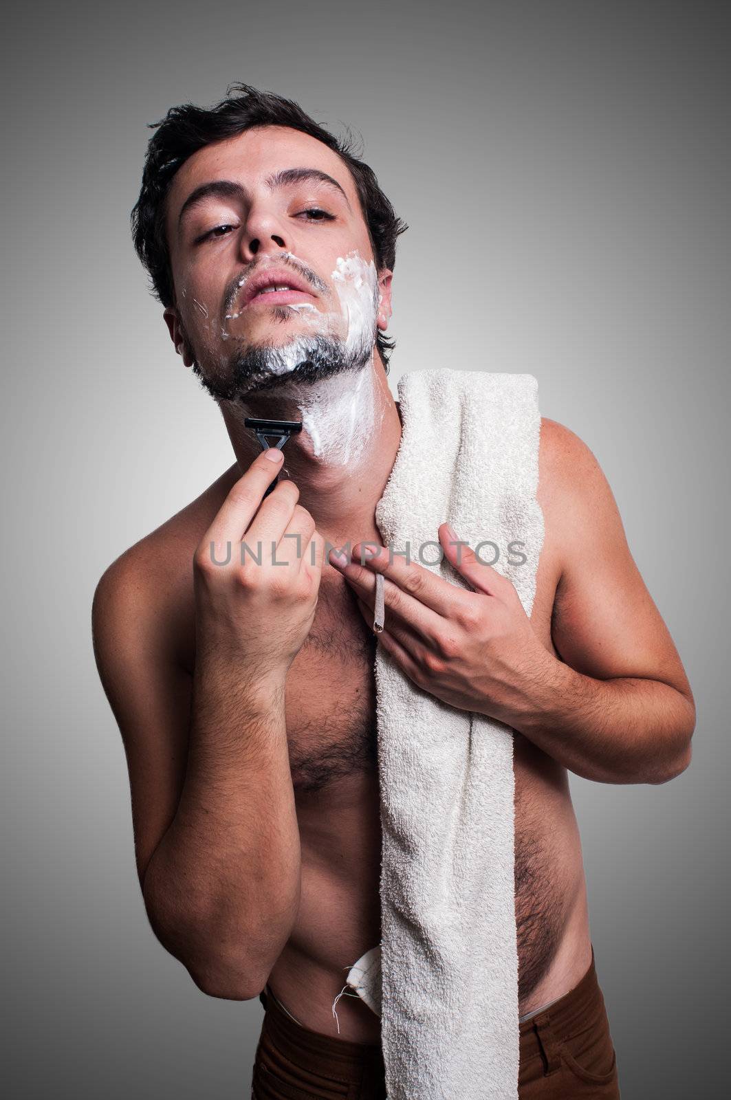 sexy man who shaves his beard on grey background