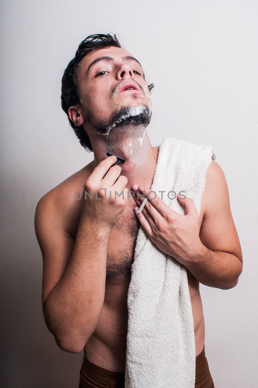 sexy man who shaves his beard on grey background