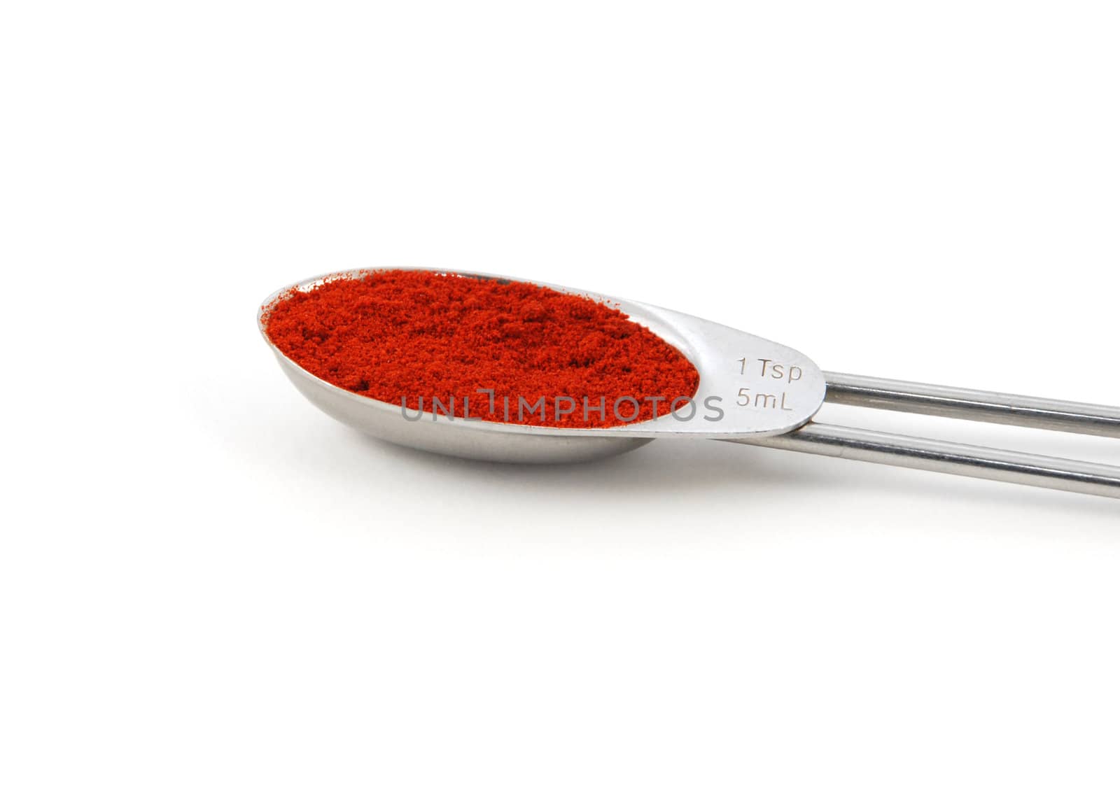Smoked paprika powder measured in a metal teaspoon, isolated on a white background