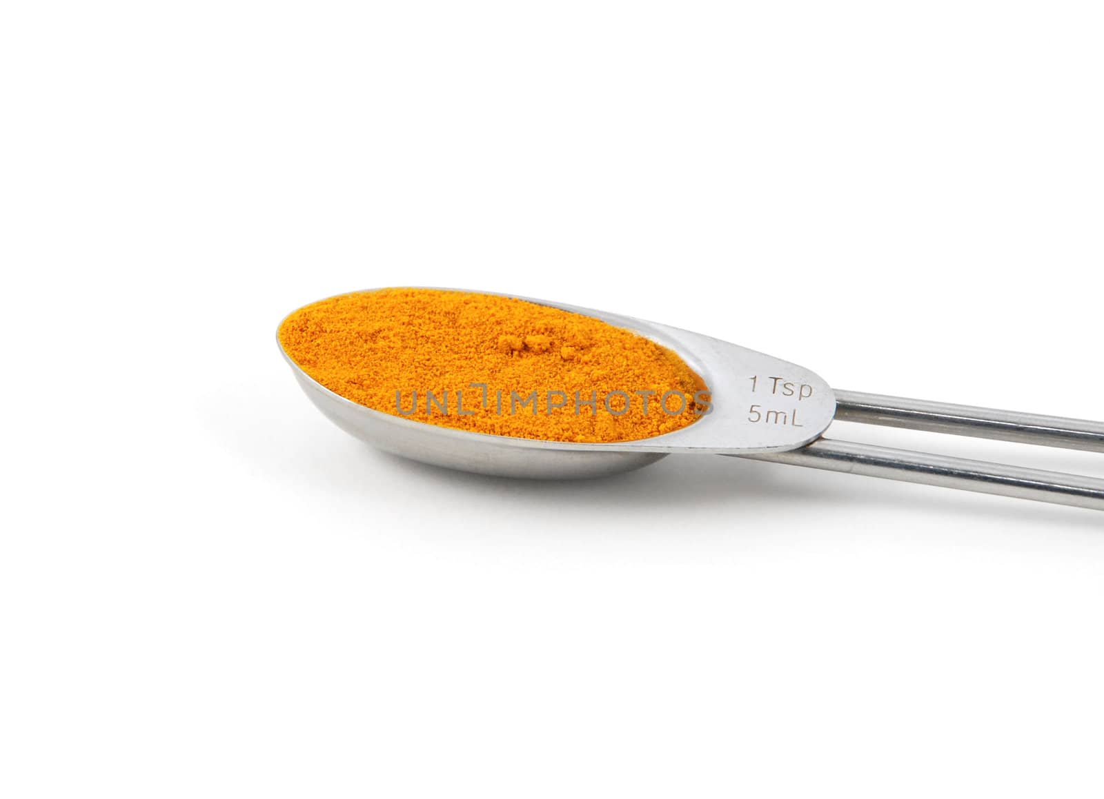 Turmeric measured in a metal teaspoon, isolated on a white background