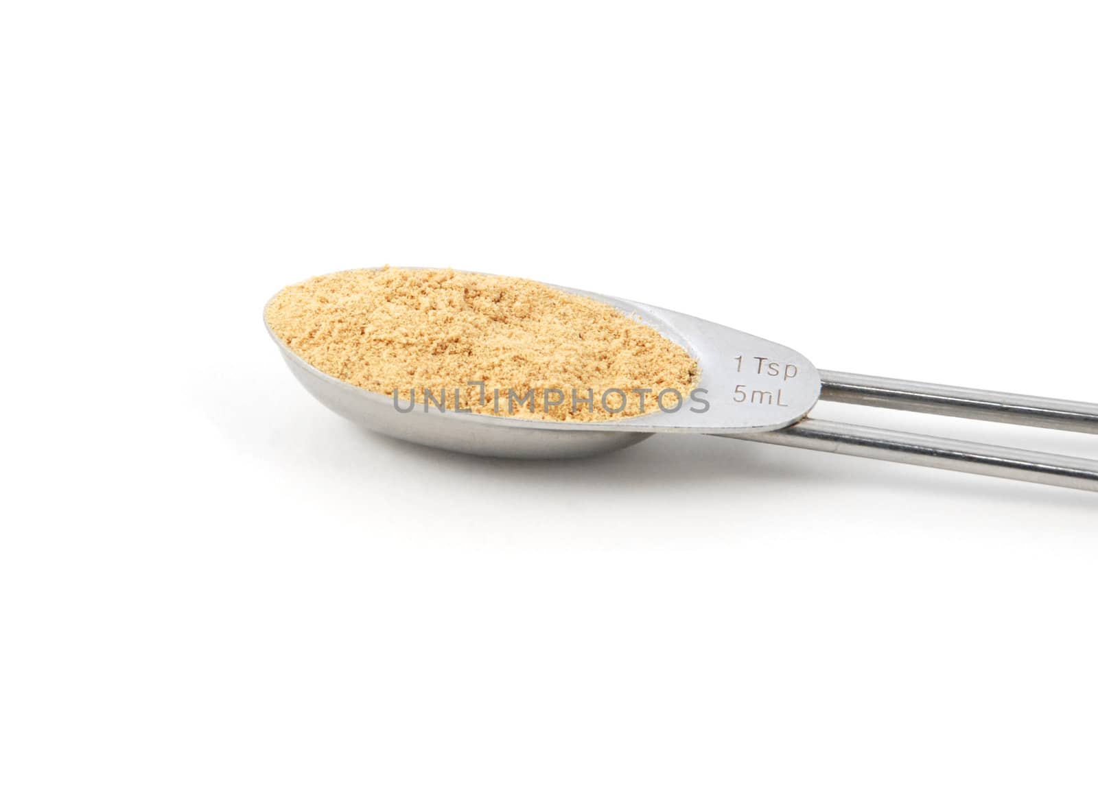 Ground ginger measured in a metal teaspoon, isolated on a white background