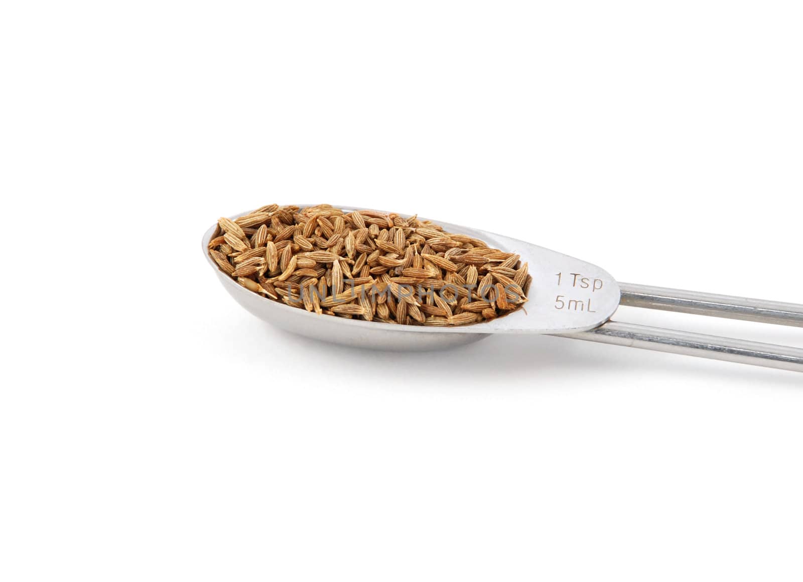 Whole cumin seeds measured in a metal teaspoon, isolated on a white background