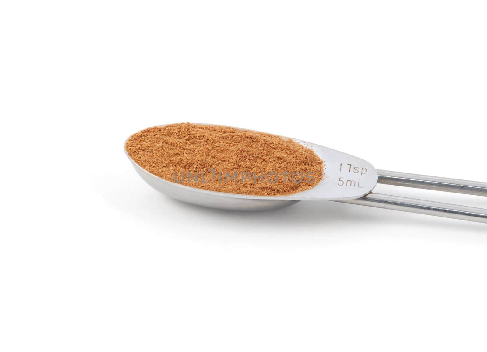 Ground cinnamon measured in a metal teaspoon, isolated on a white background