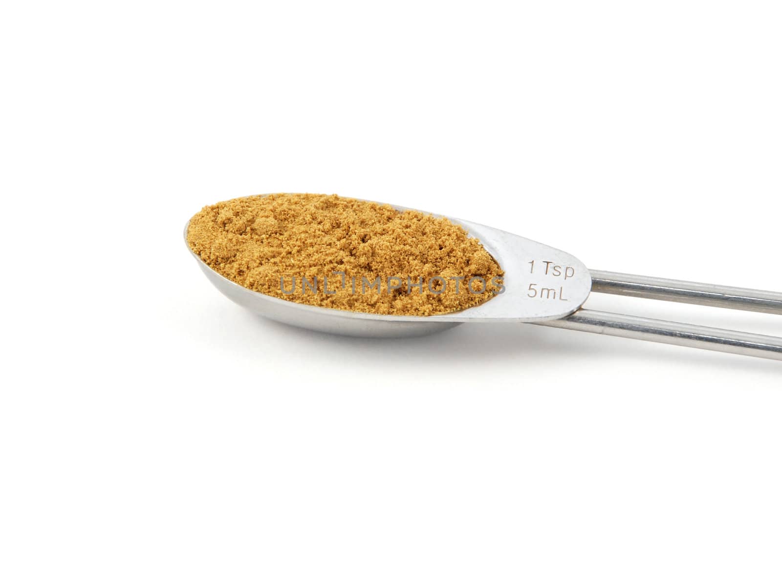 Ground cumin measured in a metal teaspoon, isolated on a white background