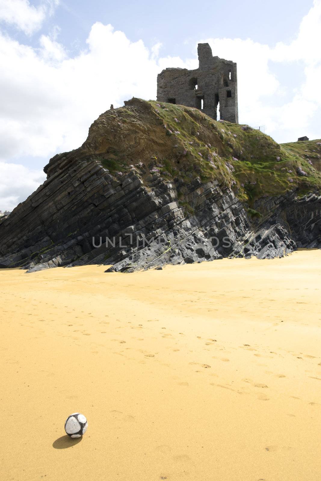 football in front of beach view of an old castle ruins in Ballybunion county Kerry Ireland