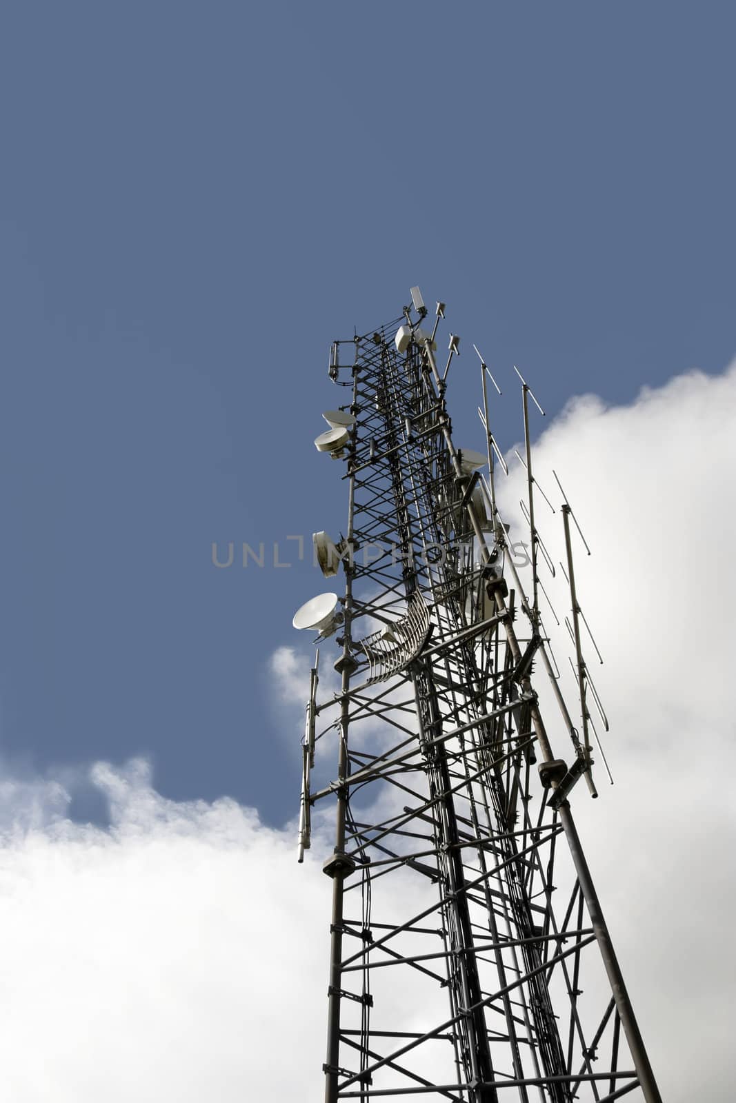 a steel telecommunication tower with a cloudy sky background