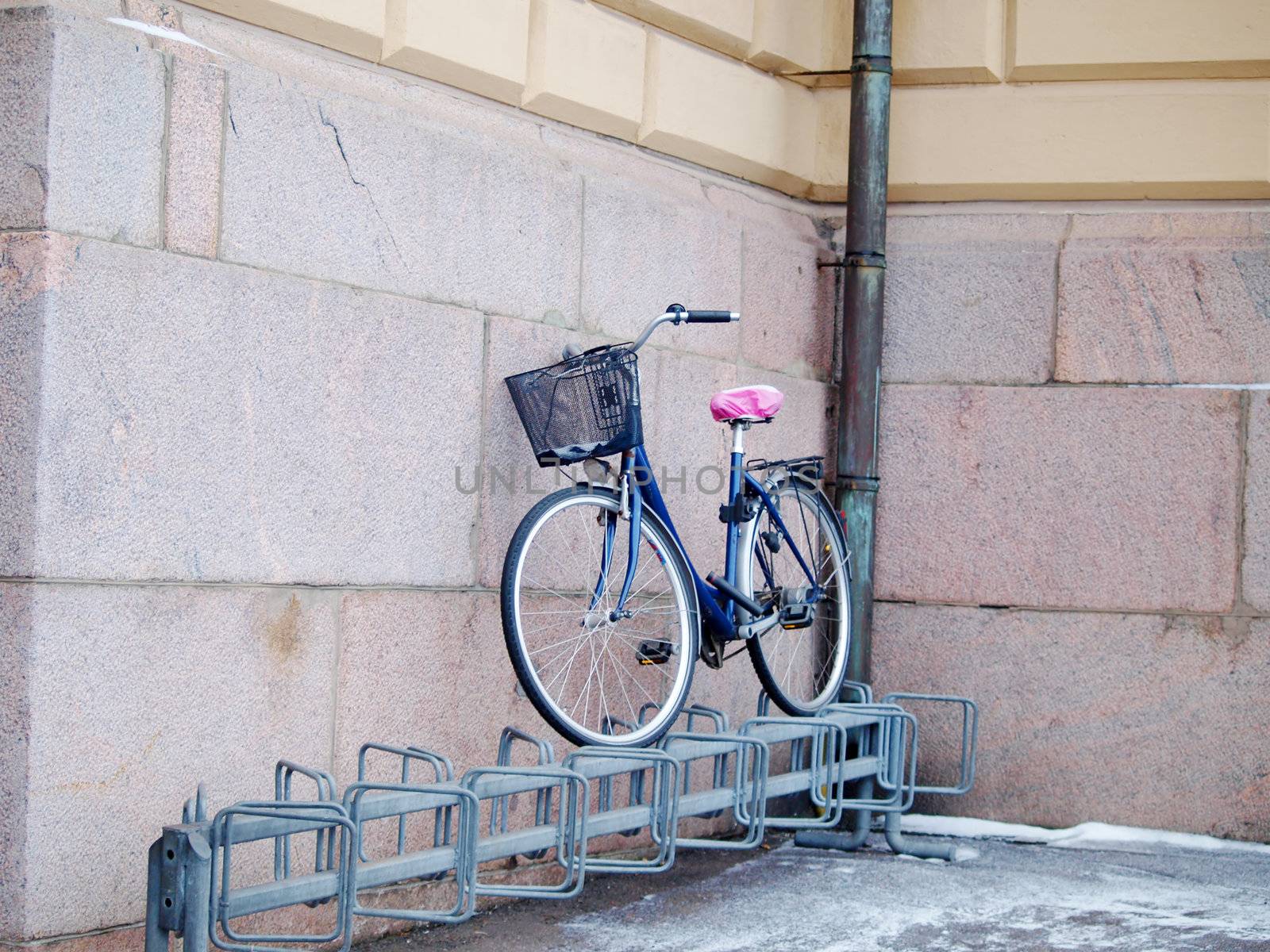 Bike left above a bike rack, towards a stone brick building