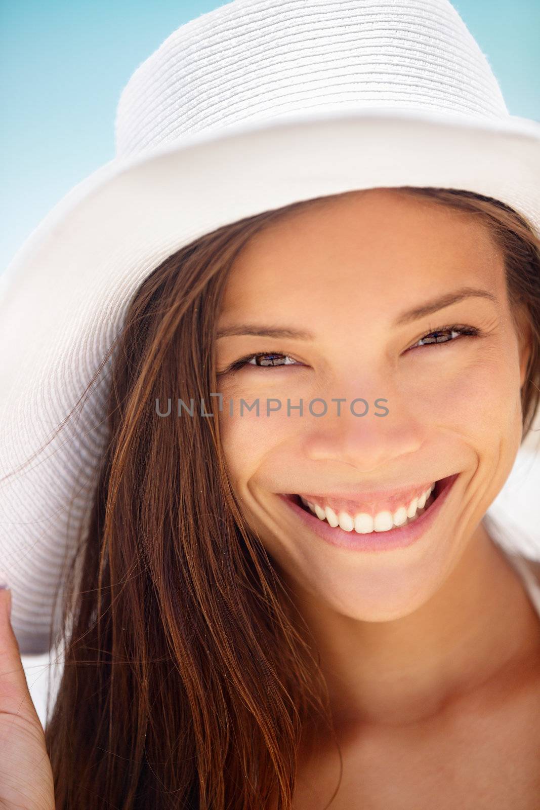 Beach woman smiling happy. Mixed race ethnic Asian and Caucasian young woman with candid fresh healthy smile outdoors wearing white beach hat.