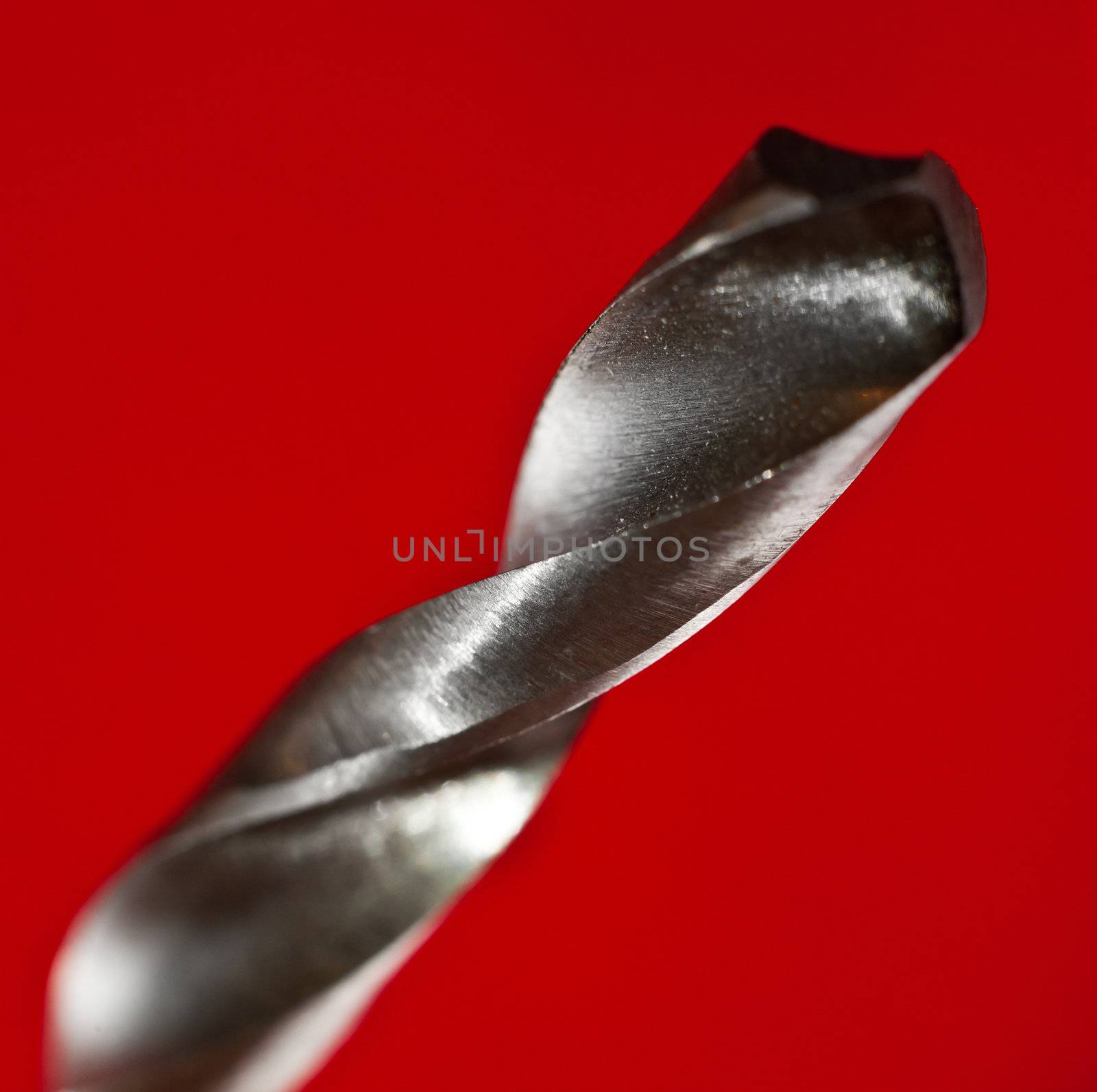 macro closeup of a metal drilling bit on red background