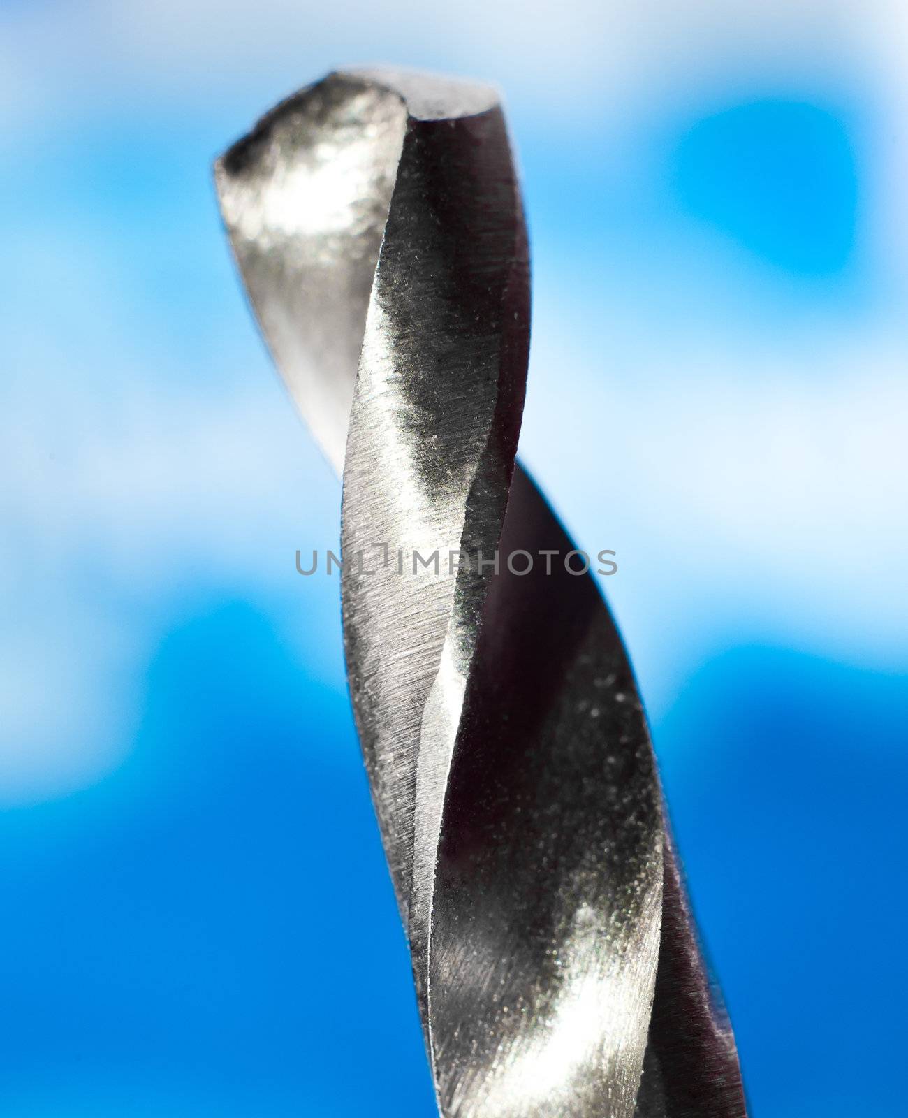 macro closeup of a metal drilling bit on blue background