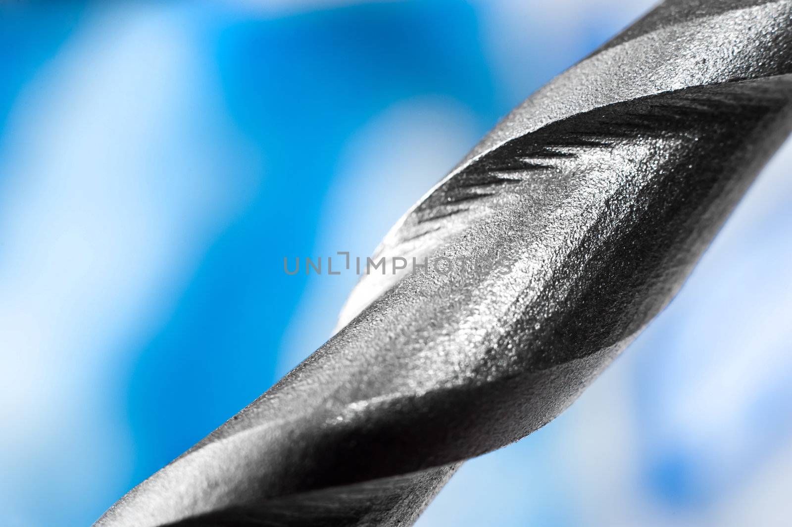 macro closeup of a metal drilling bit on blue background