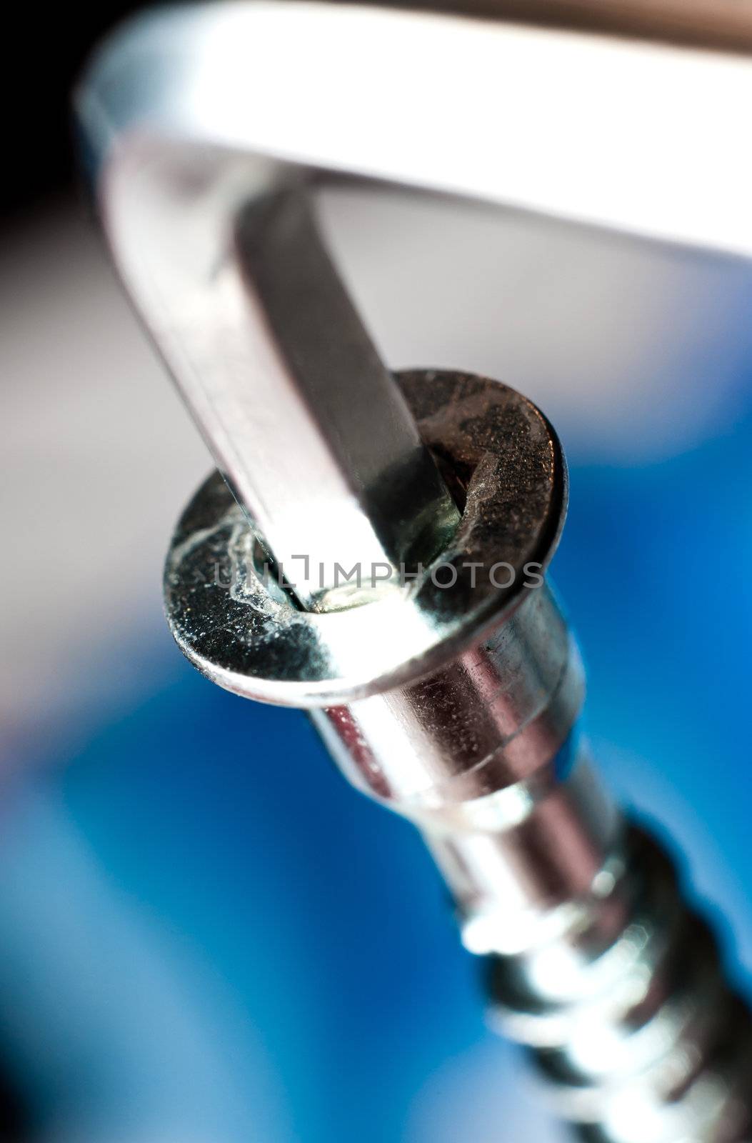 A chrome cap head or allen screw with a wrench ready to tighten