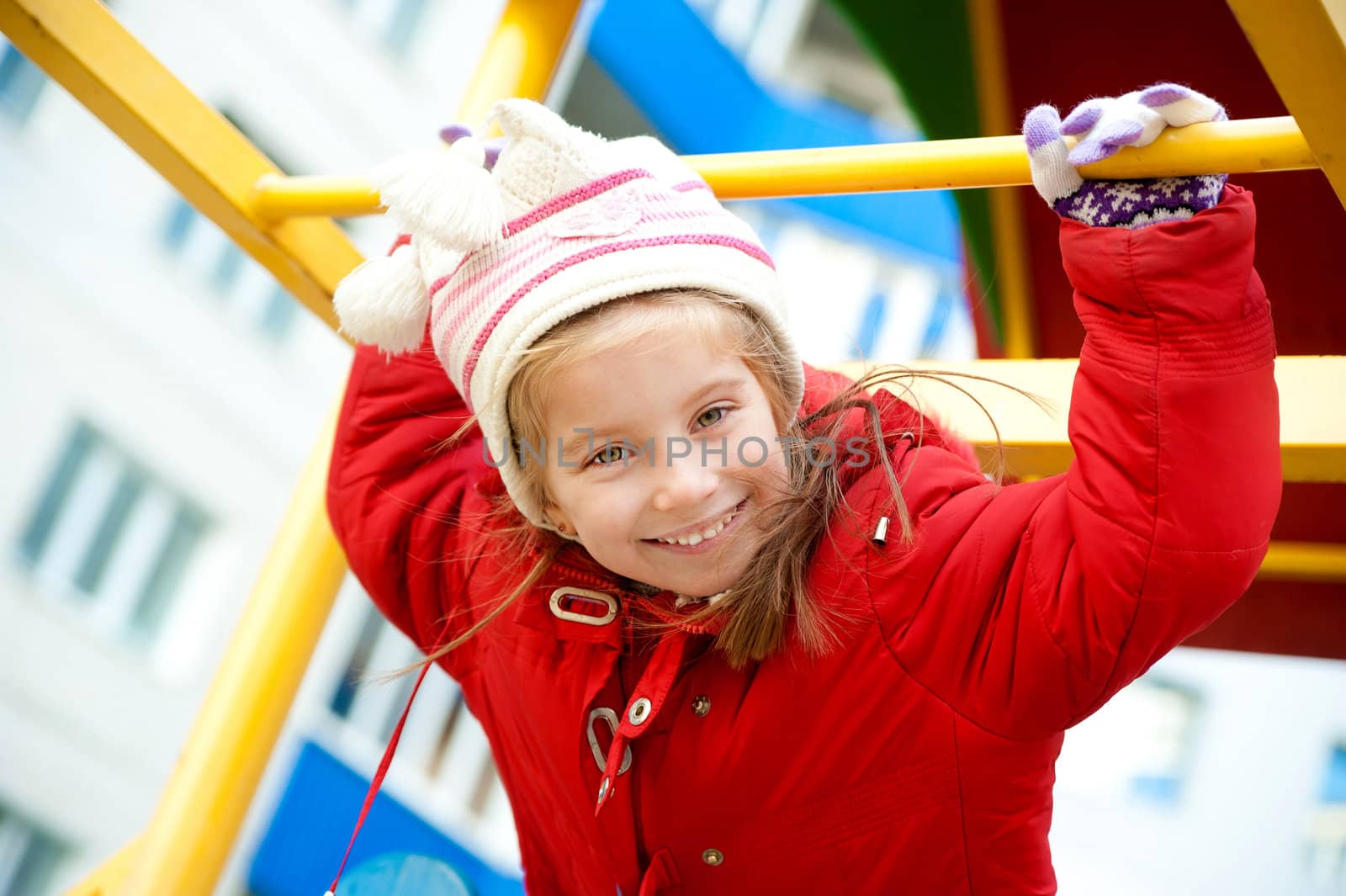 Cute little girl in red on outdoor playground equipment