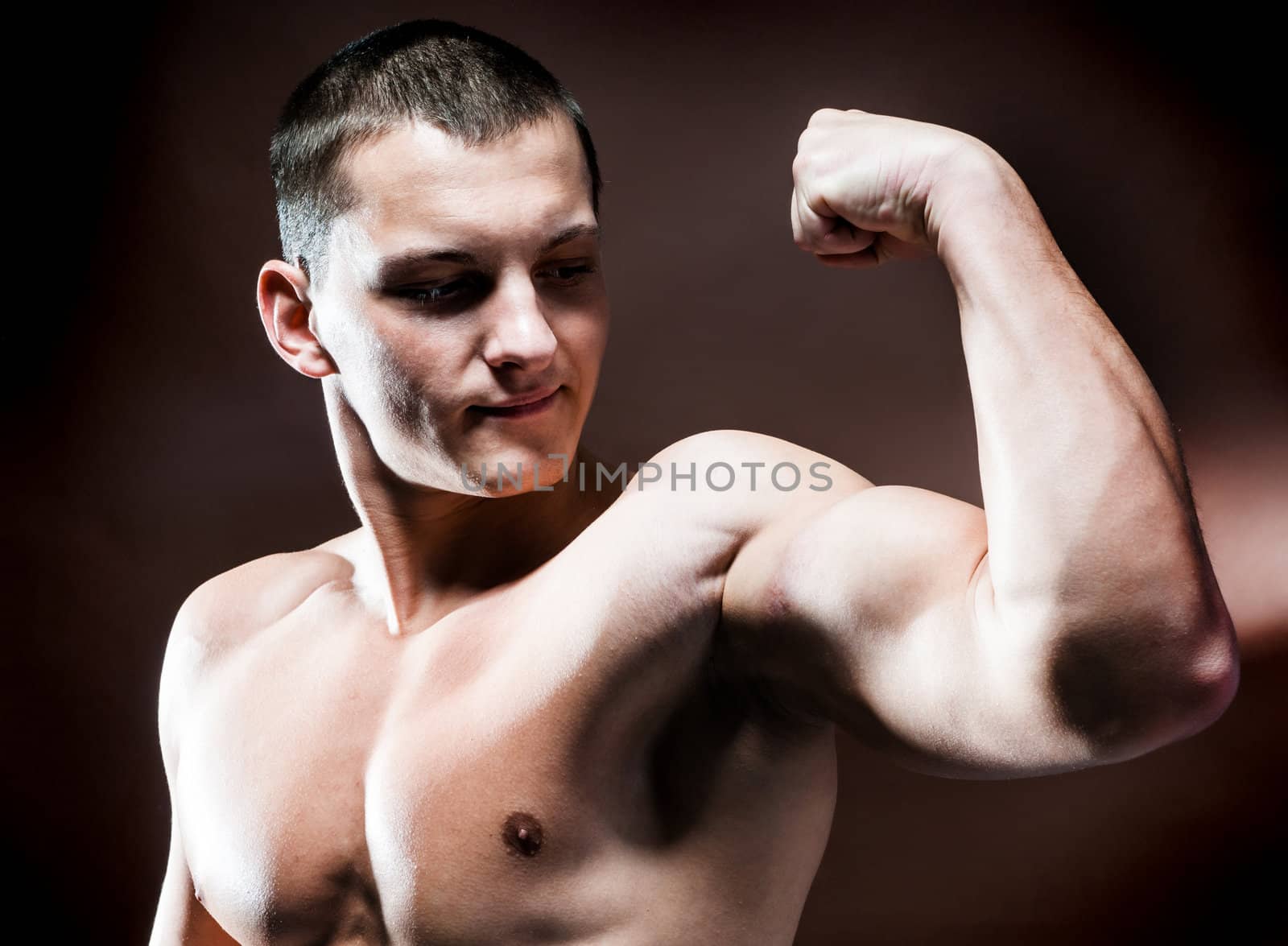 Muscular man with strong biceps on a brown background