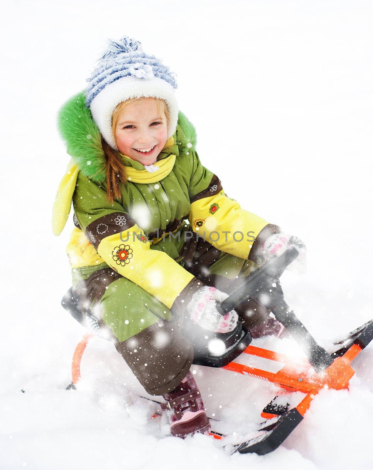 Smiling Happy litte girl with children's snowmobile