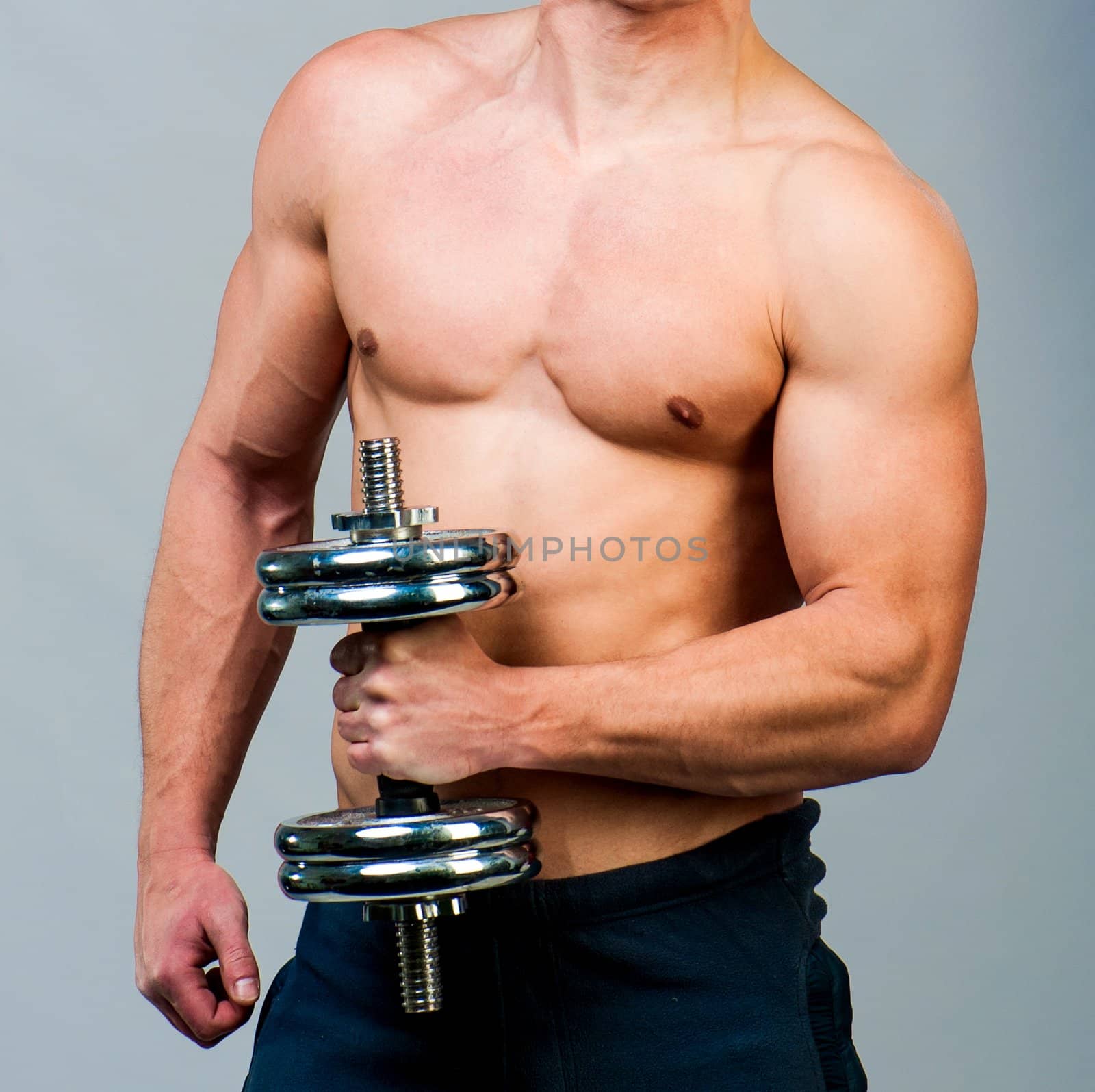 attractive athletic male torso with dumbbells in hand