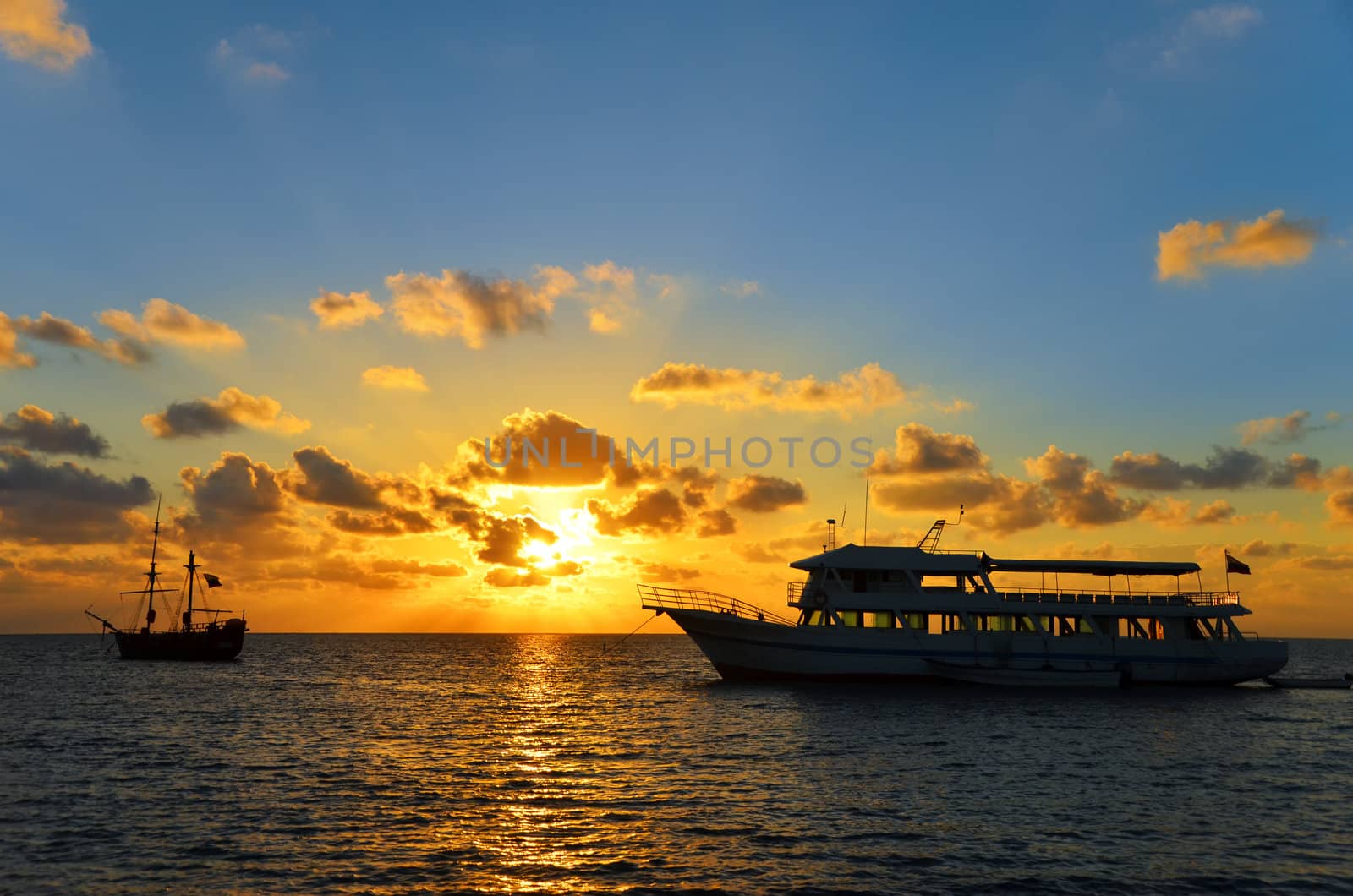 Sunrise in San Andres, Colombia over an old pirate ship and a modern ship
