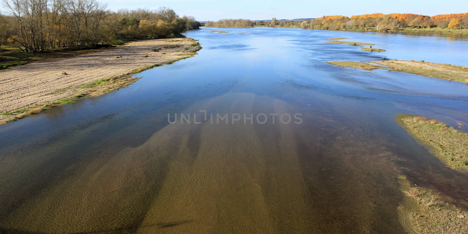 landscape of a wild river with islands and sand bordered by trees in view