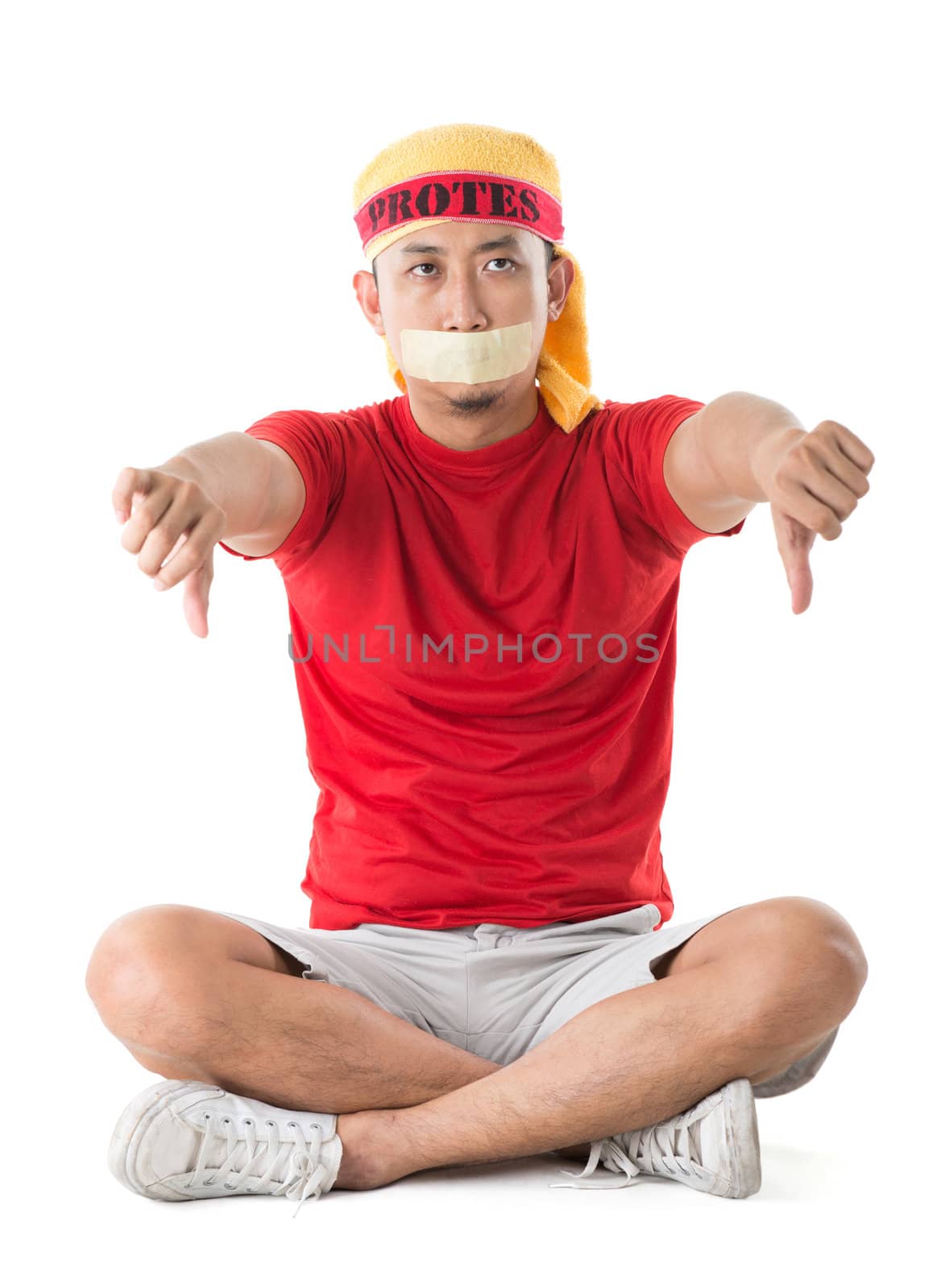 People protest concept. Southeast Asian protestor mouth covered thumbs down sitting on white background