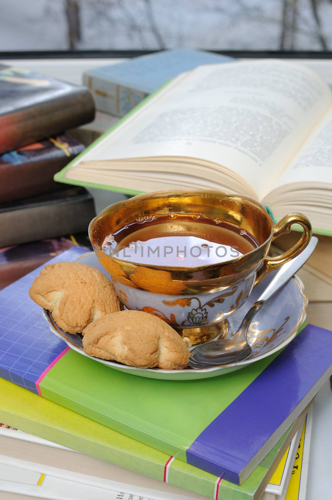 A cup of tea and biscuits on the table with books