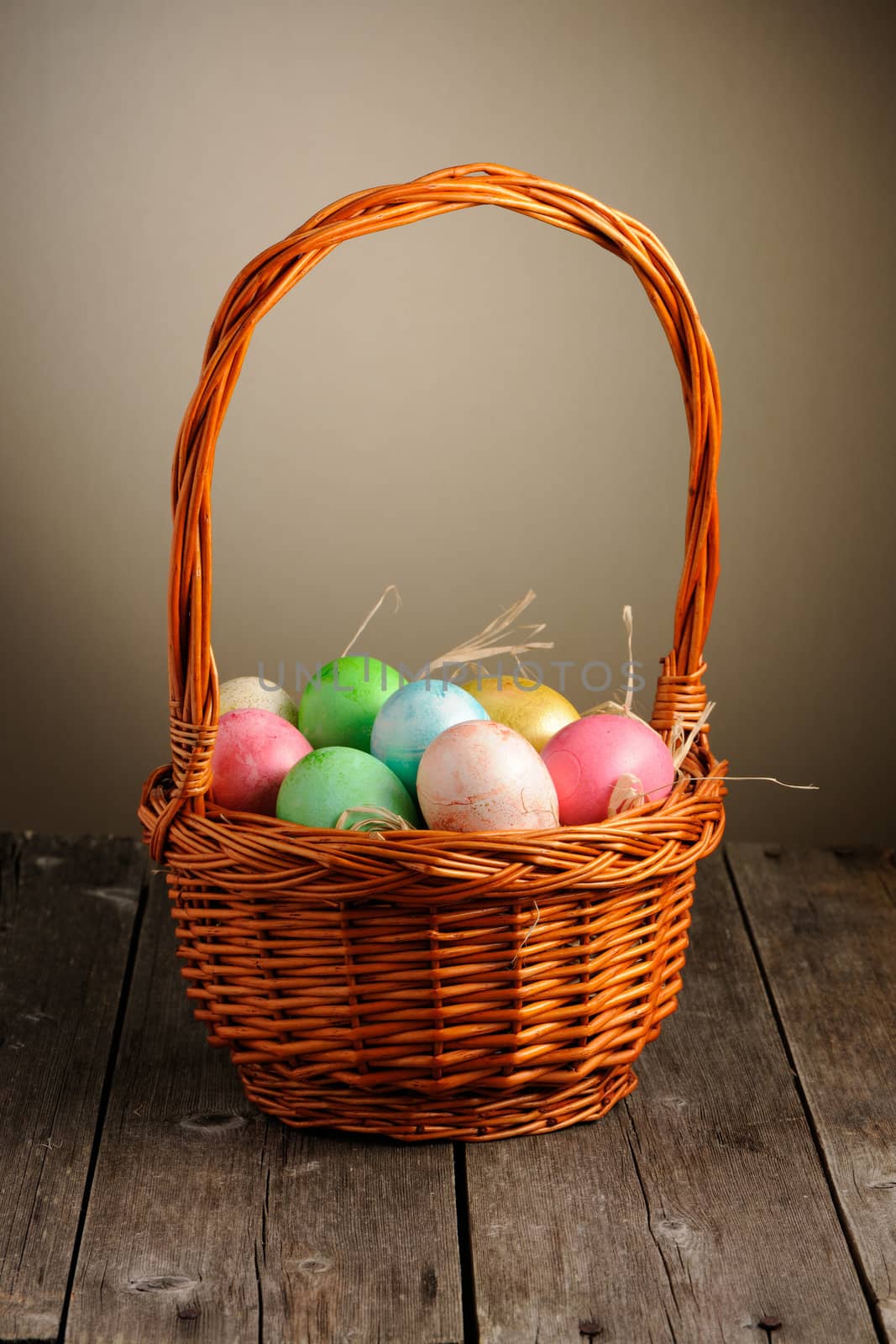 Colored easter eggs in basket on wooden table
