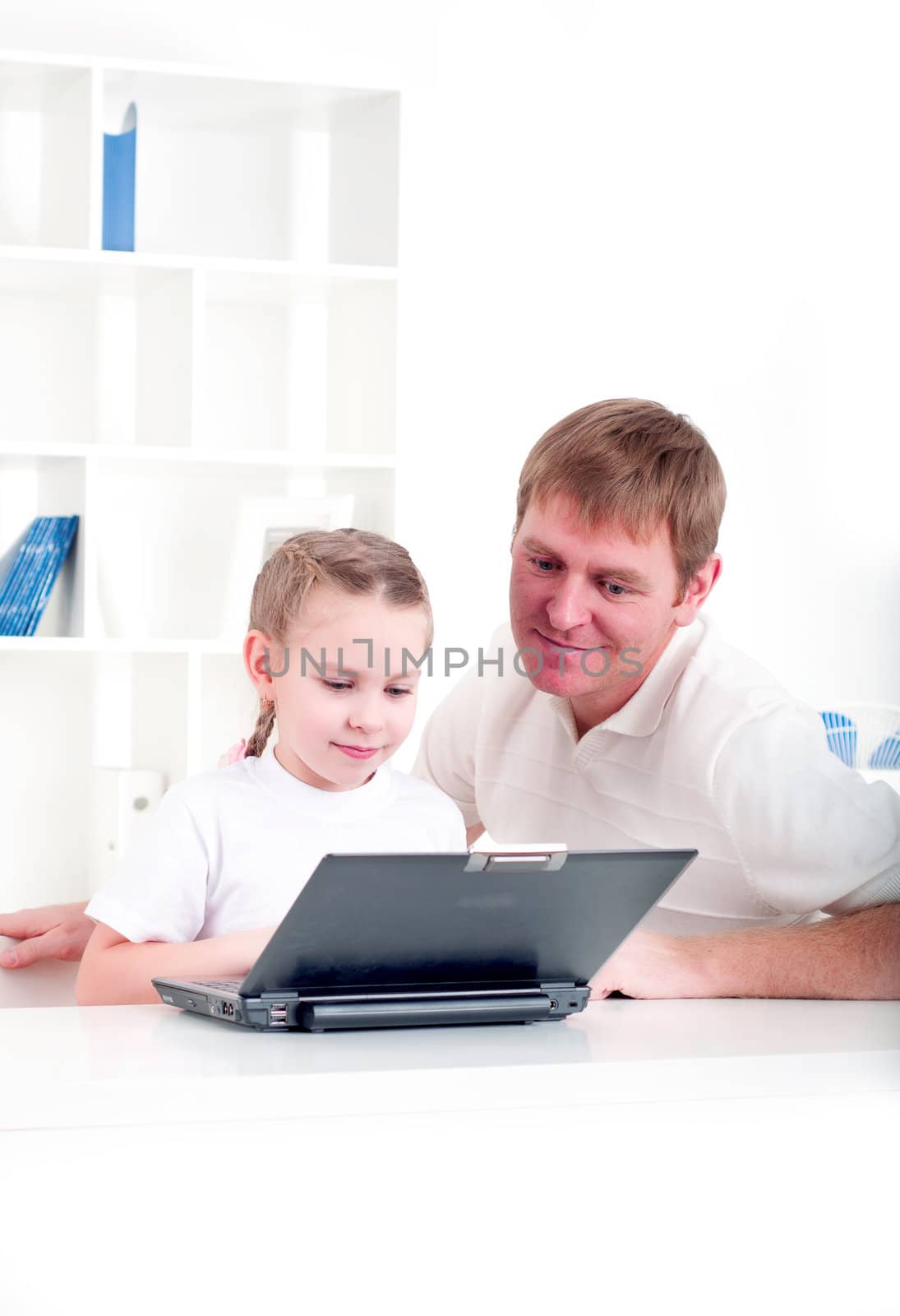 Father and daughter are working together for a laptop at home