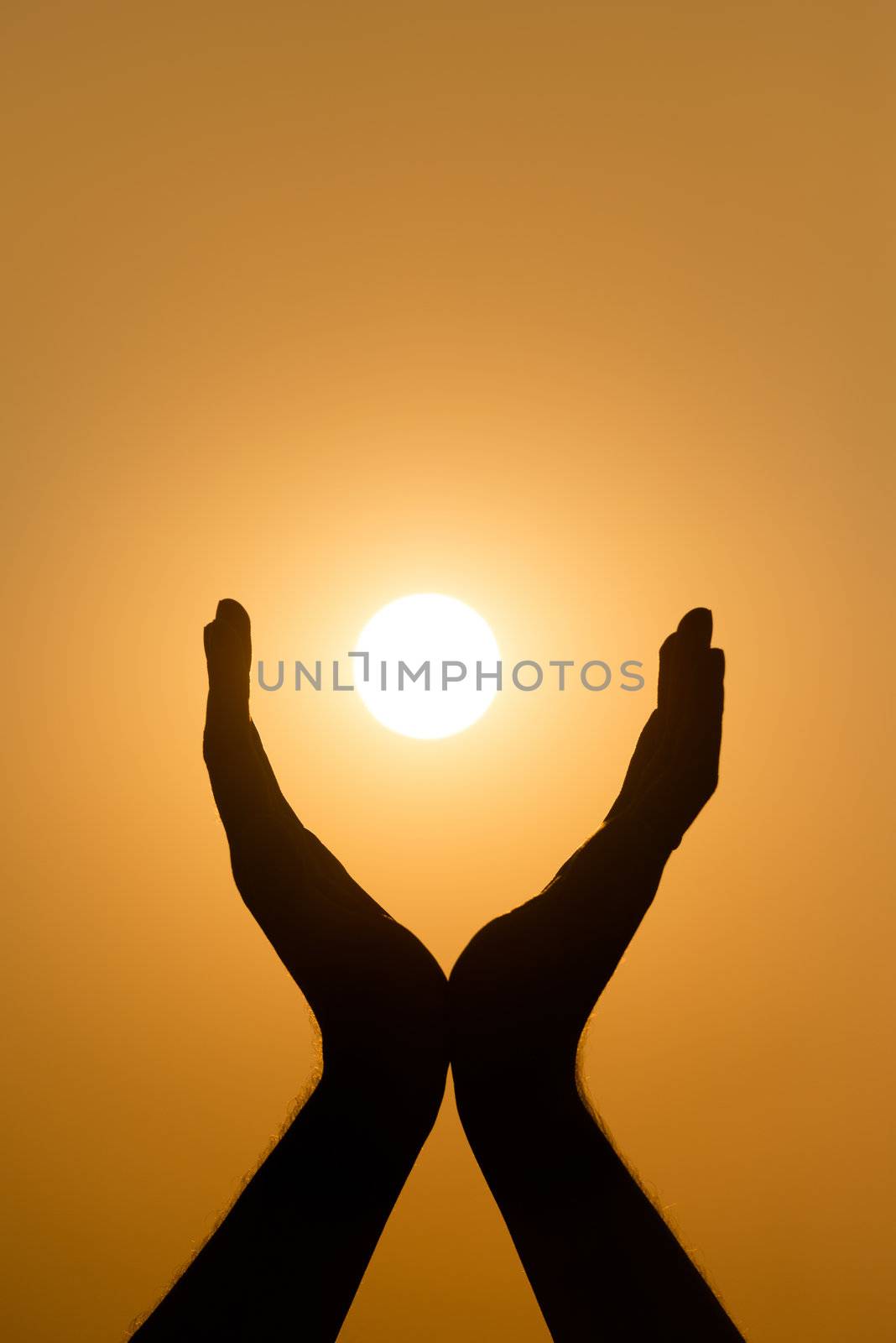 Hands holding the sun at yellow sunset background