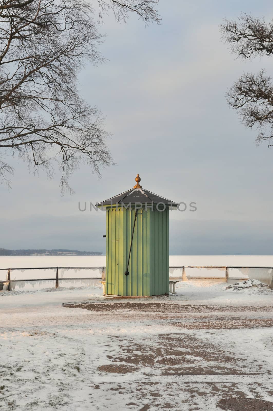 Green old pump house by the water a sunny winter day.
