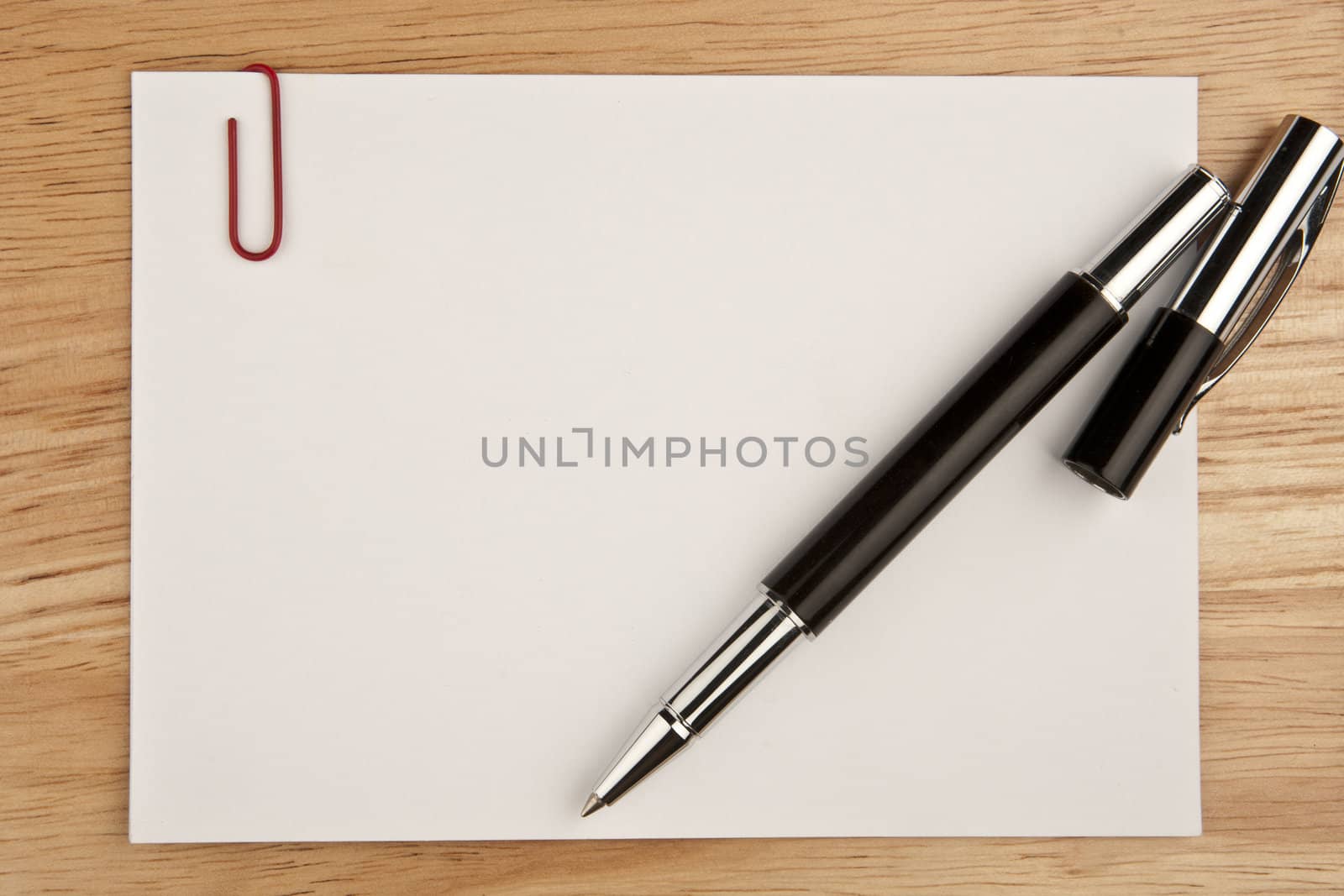 Blank sheet of paper with pen on wooden background by DGolbay