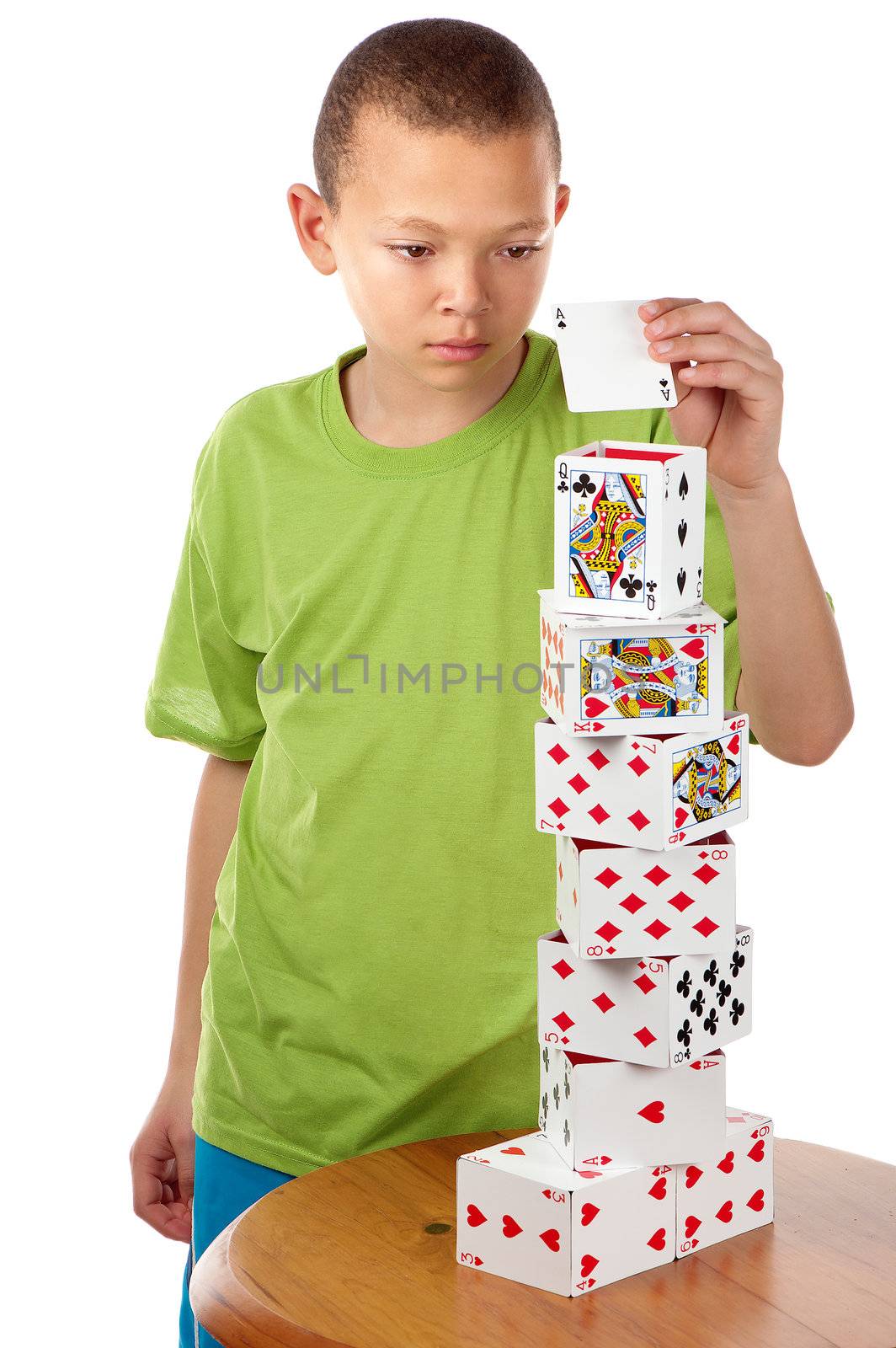 A hard concentrating boy completes his playing card tower project by placing the last card on top of it.