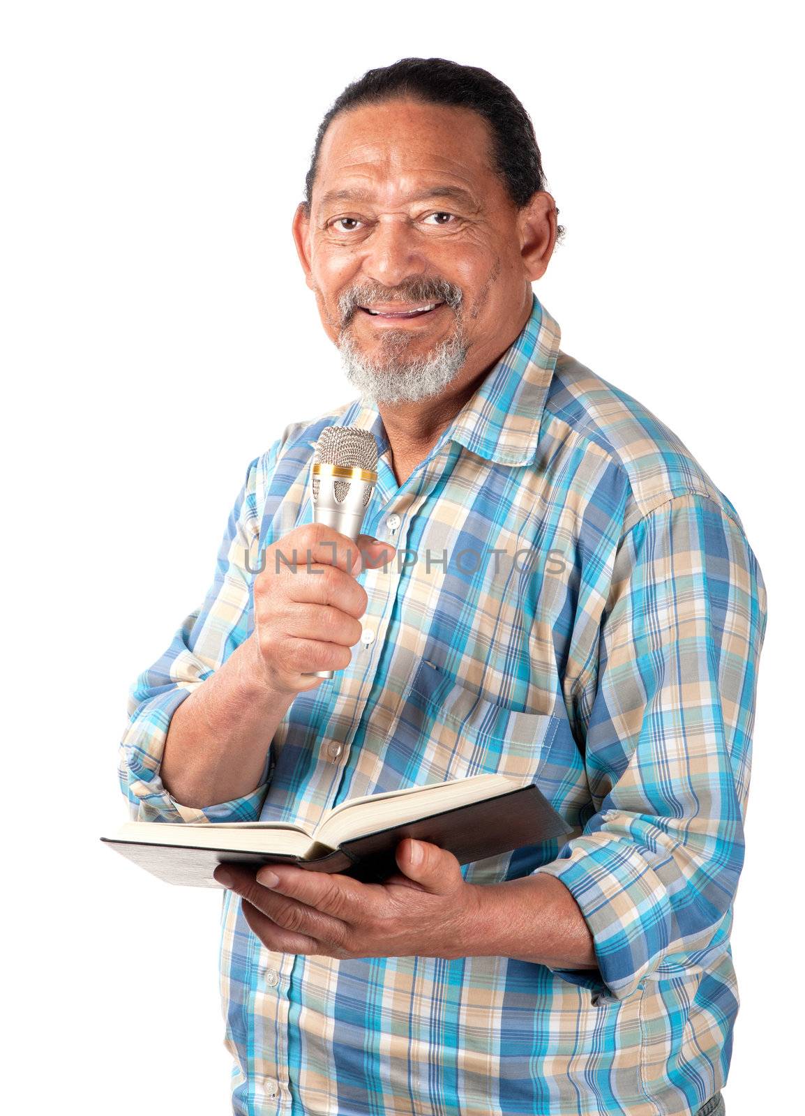 A senior preacher with a microphone and book appears as happy as can be.