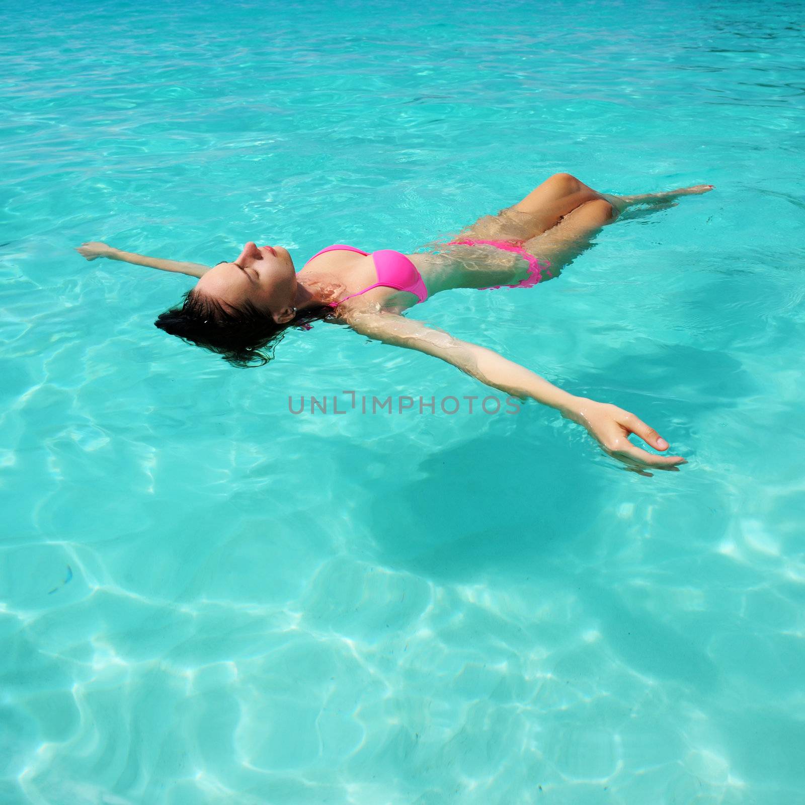 Woman in bikini lying on water  by haveseen