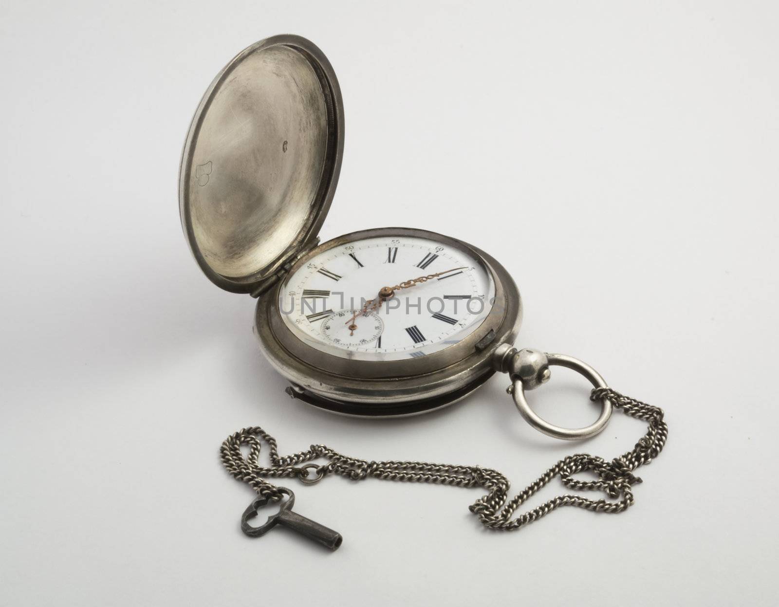 Antique pocket watch in silver with small key on a light background. Appearance with the lid open.